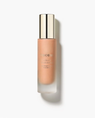 Bottle of peach-colored liquid makeup or skincare product with a gold cap against a white background.