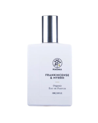White perfume bottle with a silver cap and a minimalist label, featuring the Hanoma logo and text indicating fragrance with frankincense and myrrh.