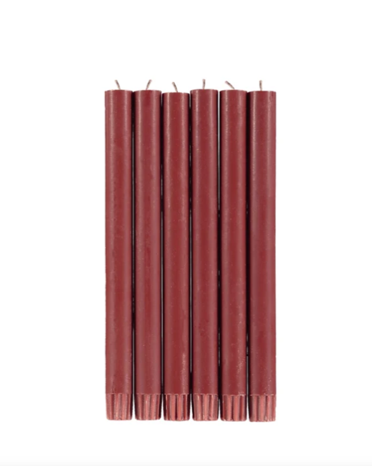 Six red candles standing upright on a white background.
