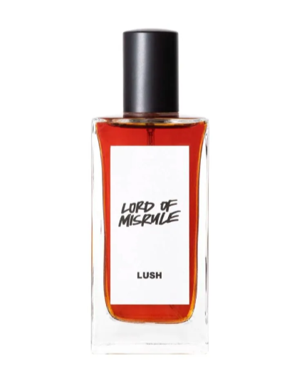 A bottle of Lush perfume named 'Lord of Misrule' with red liquid inside, clear glass, and a black cap.