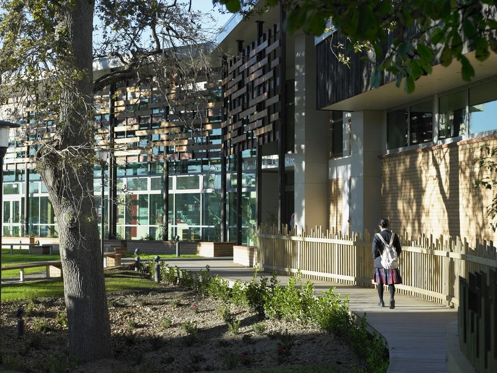 Highschool sports education centre, schoolgirl walks up the path into the building