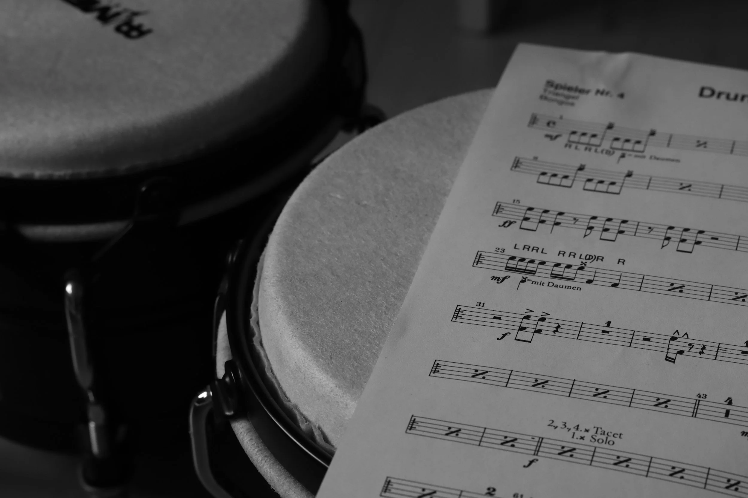 Sheet music on a round table with a drum in the background.