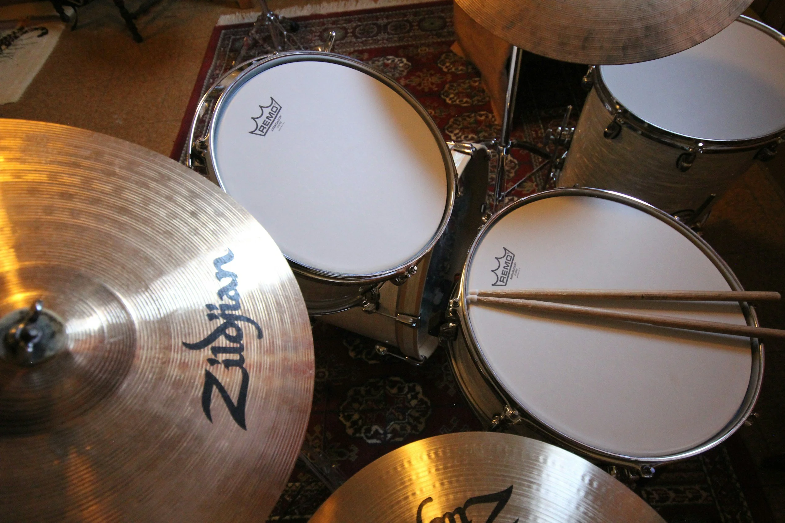 A drum set with multiple drums and cymbals, arranged on a carpeted floor.