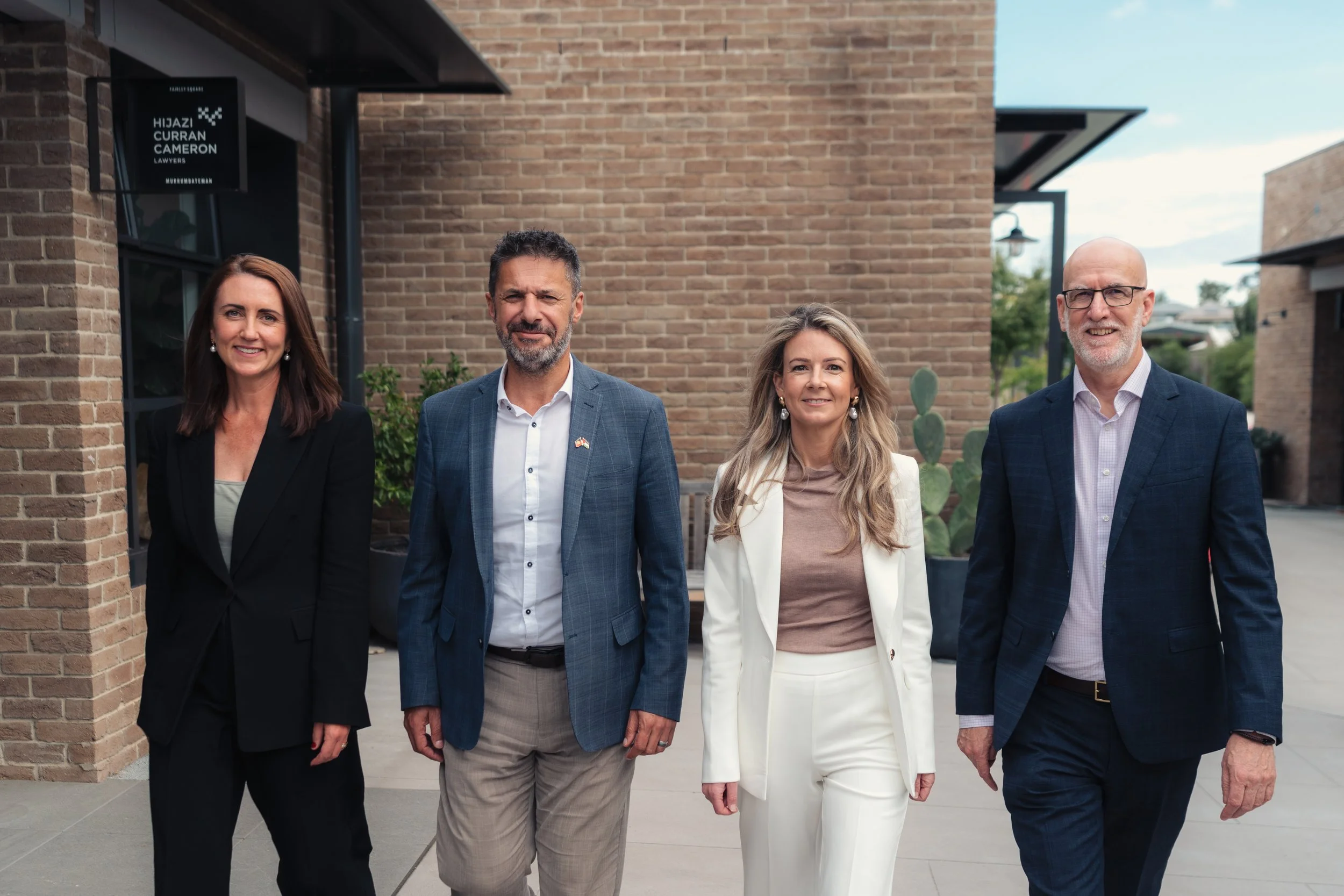 HCC Lawyers teamstanding outside in front of a brick building, smiling at the camera.