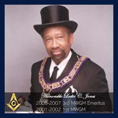 A man wearing a traditional Masonic apron and top hat, dressed in formal attire, with a gray background.