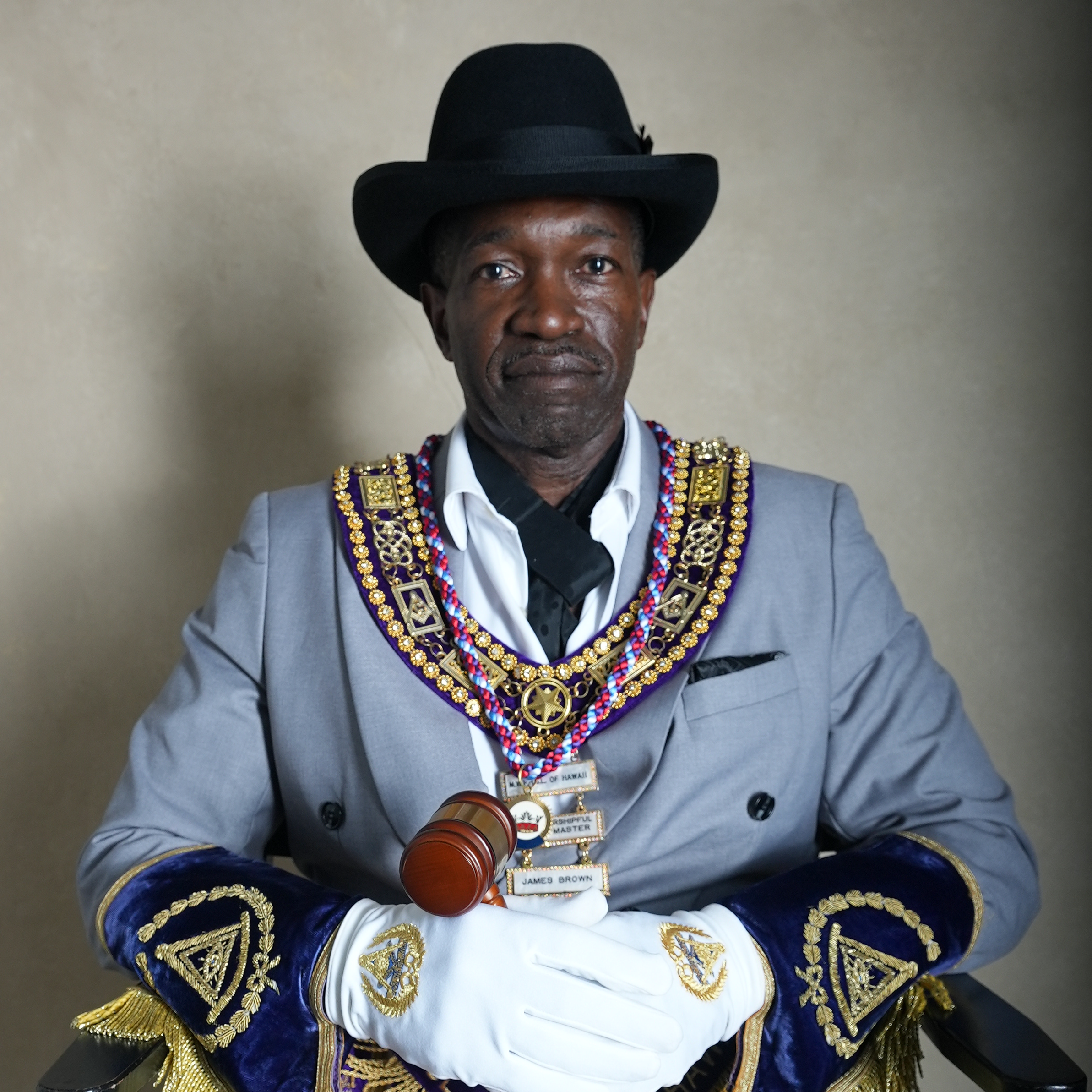A man in a suit wearing a chain of office and a top hat, holding a gavel, smiling, with the name 'MW J. BROWN' written below.