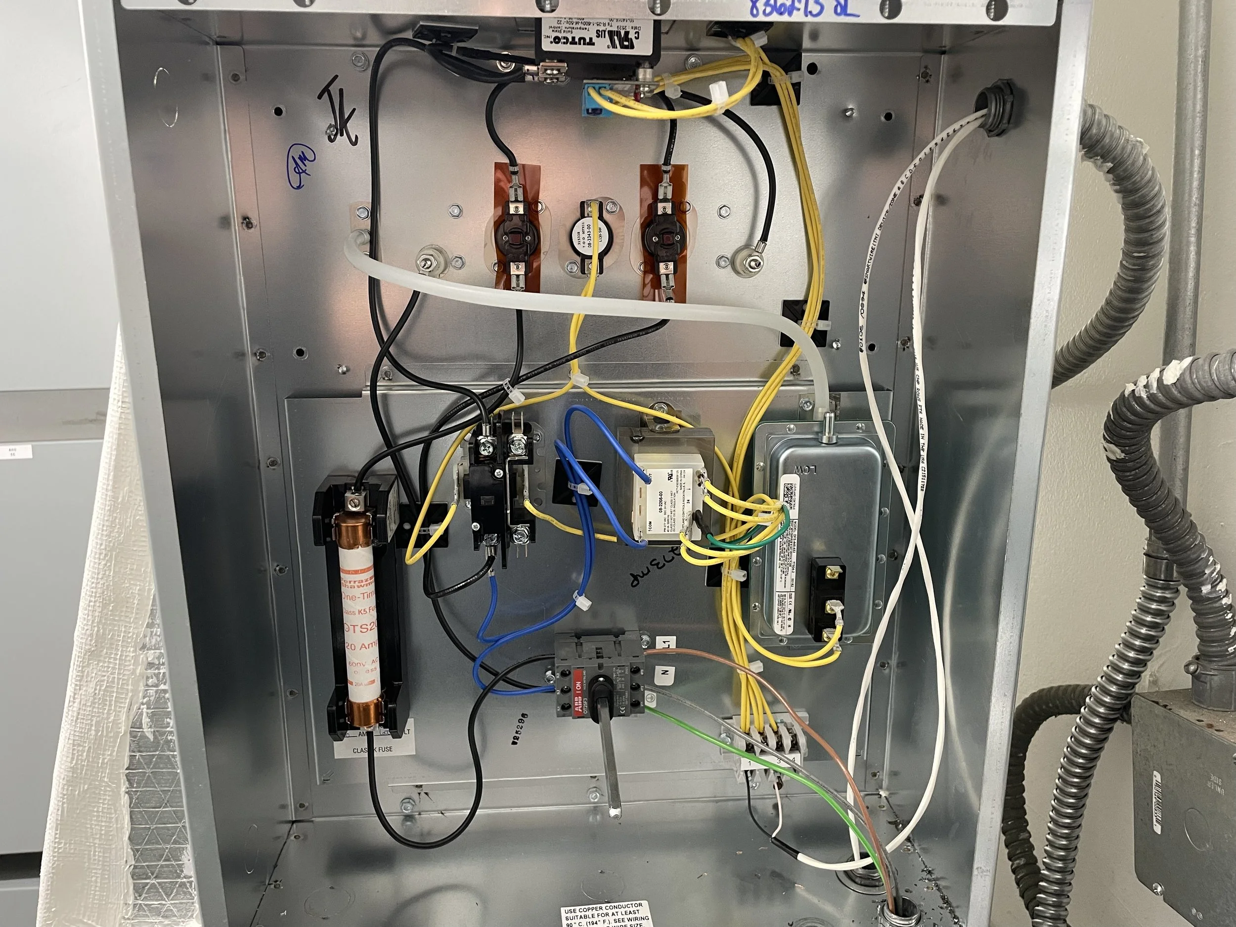 The interior of an electrical control box with various wires, circuit breakers, and electrical components.