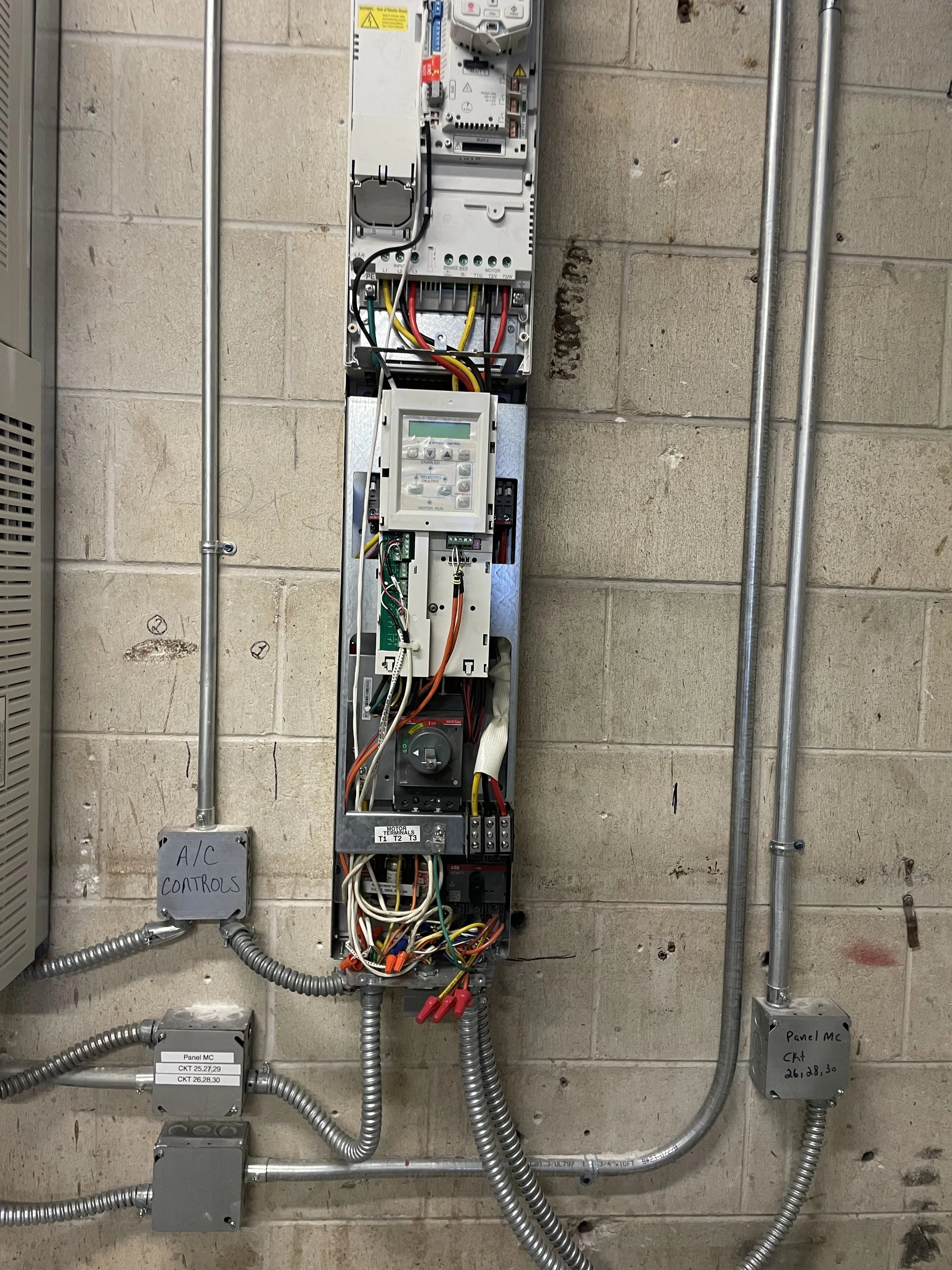 Cooling Tower VFD and wiring on a concrete wall, labeled as for A/C controls and panels.