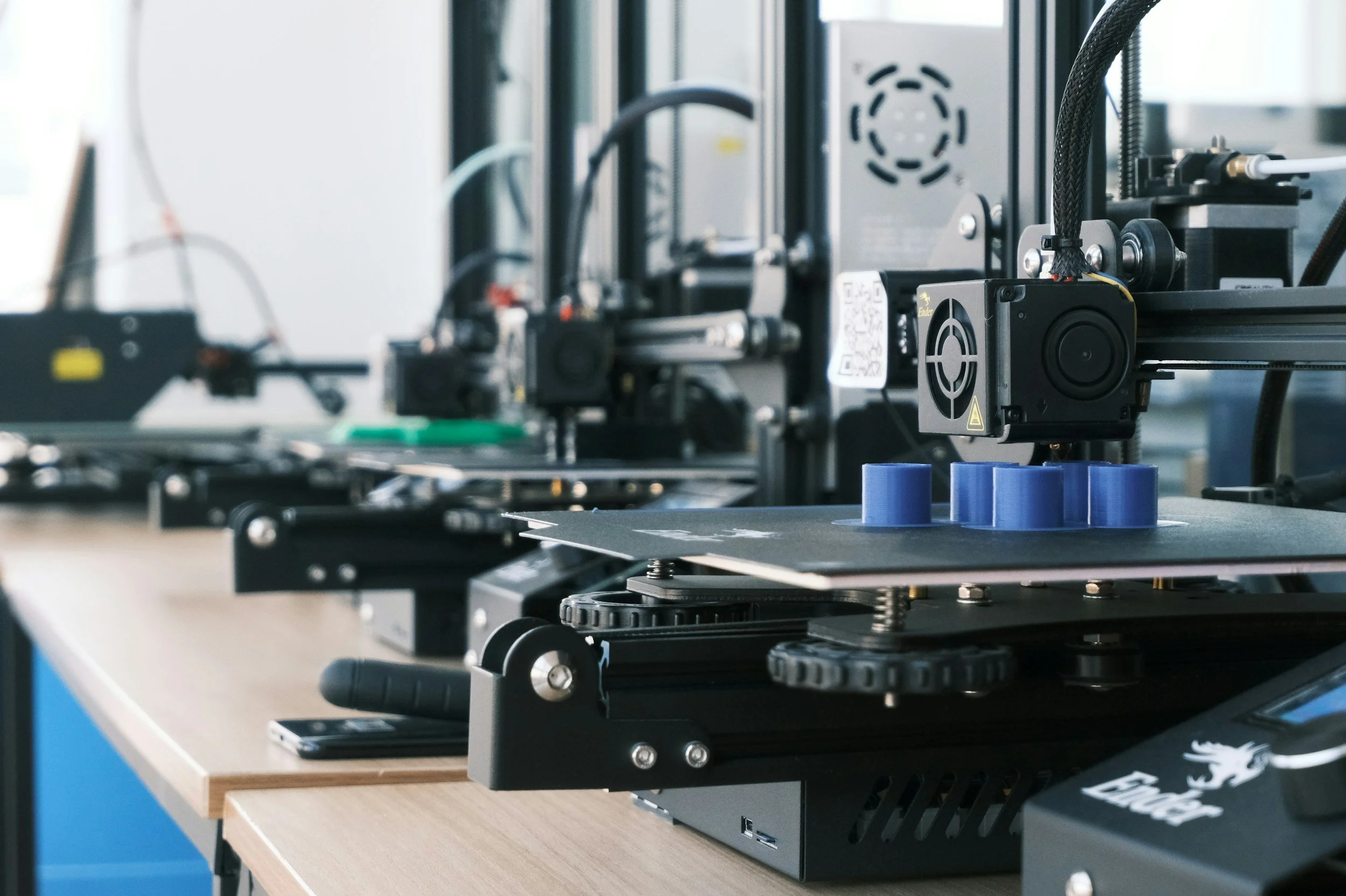 Close-up of a 3D printer on a wooden table in a workshop.