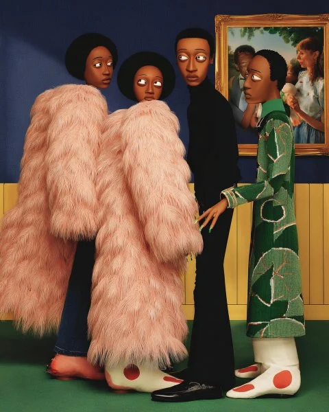 Four large mannequins with stylized features and fashion-forward clothing, including two dressed in pink fluffy coats, one in a black dress, and one in a green patterned dress, are displayed in an art gallery with a dinosaur painting in the background.