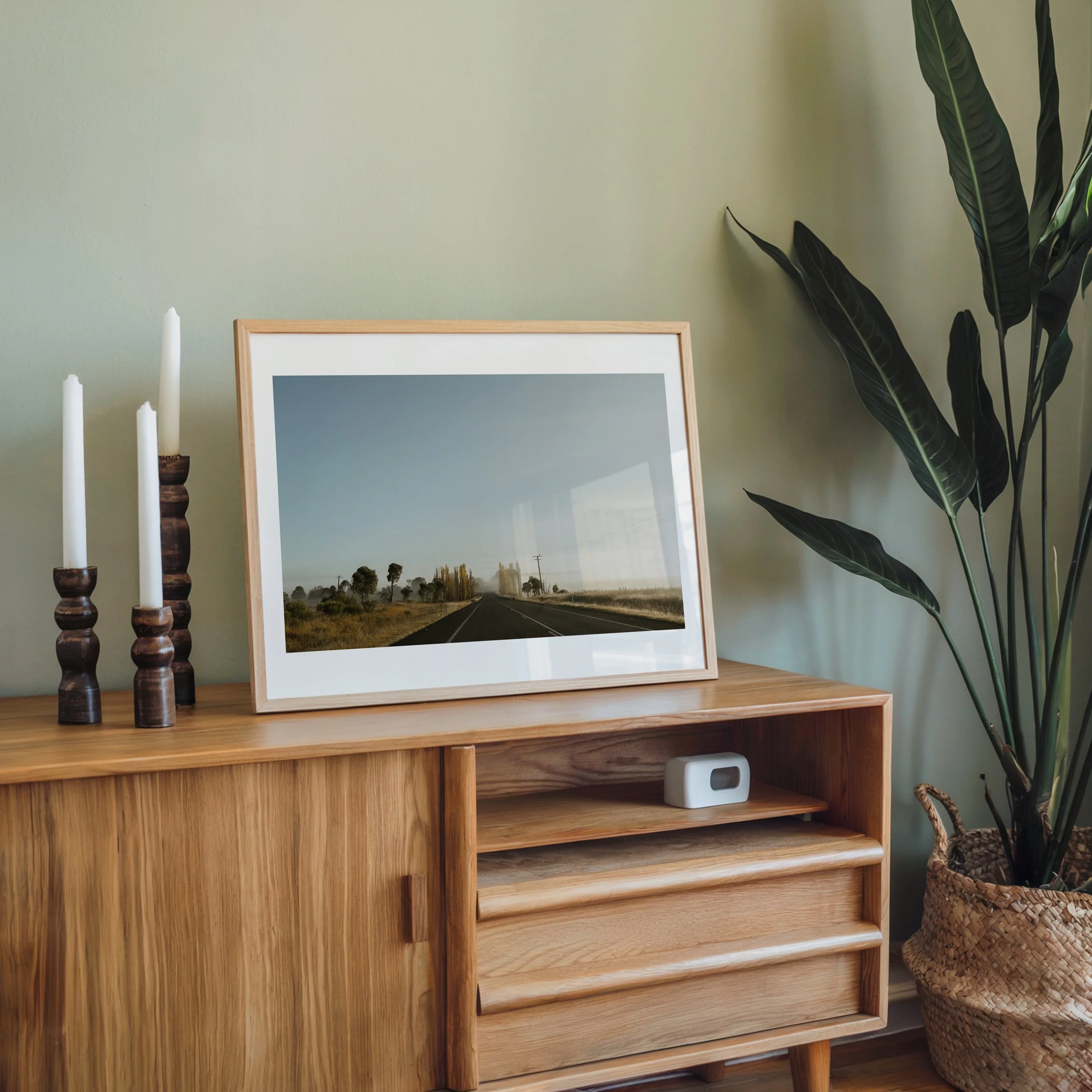 Country‑road landscape print styled as wall art in a modern interior