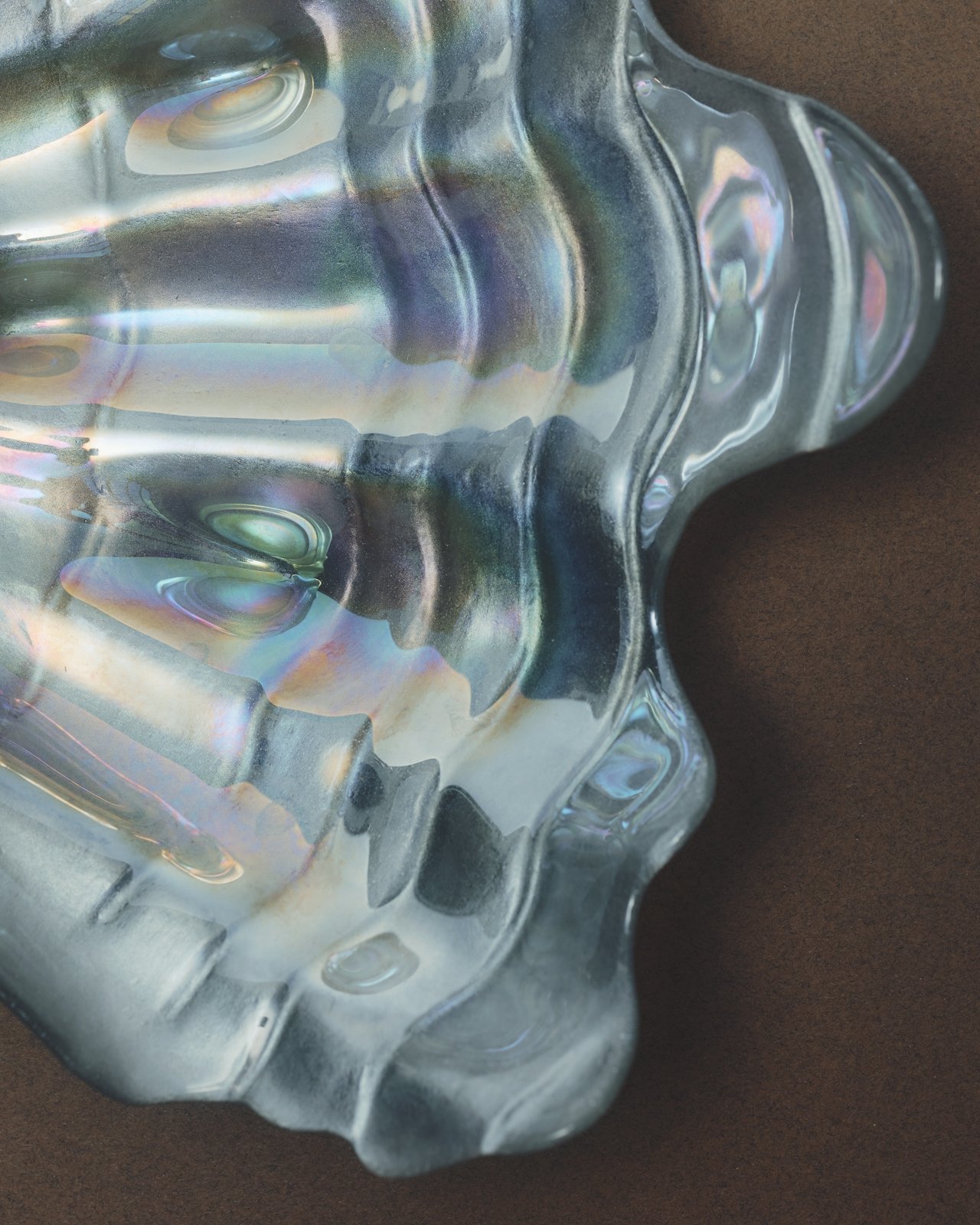 Close-up of a decorative glass object with iridescent highlights, sitting on a dark surface.