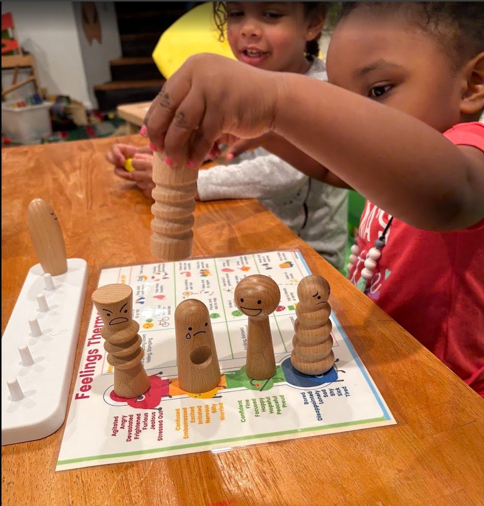Two children playing a game with wooden peg dolls at a table.