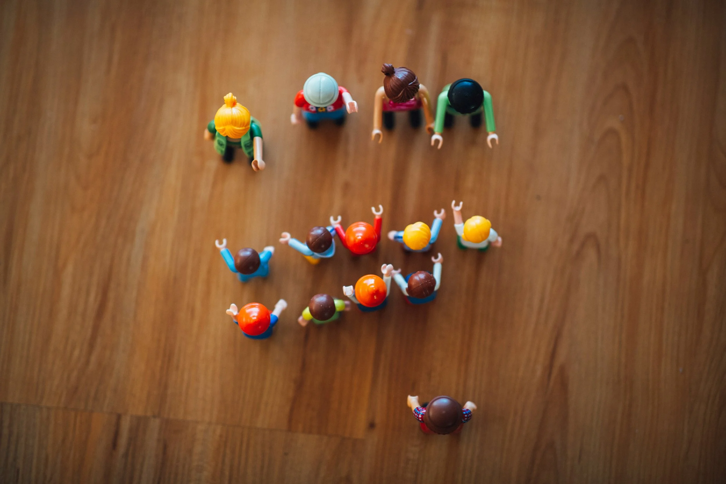 Top-down view of colorful toy figurines arranged on a wooden surface.