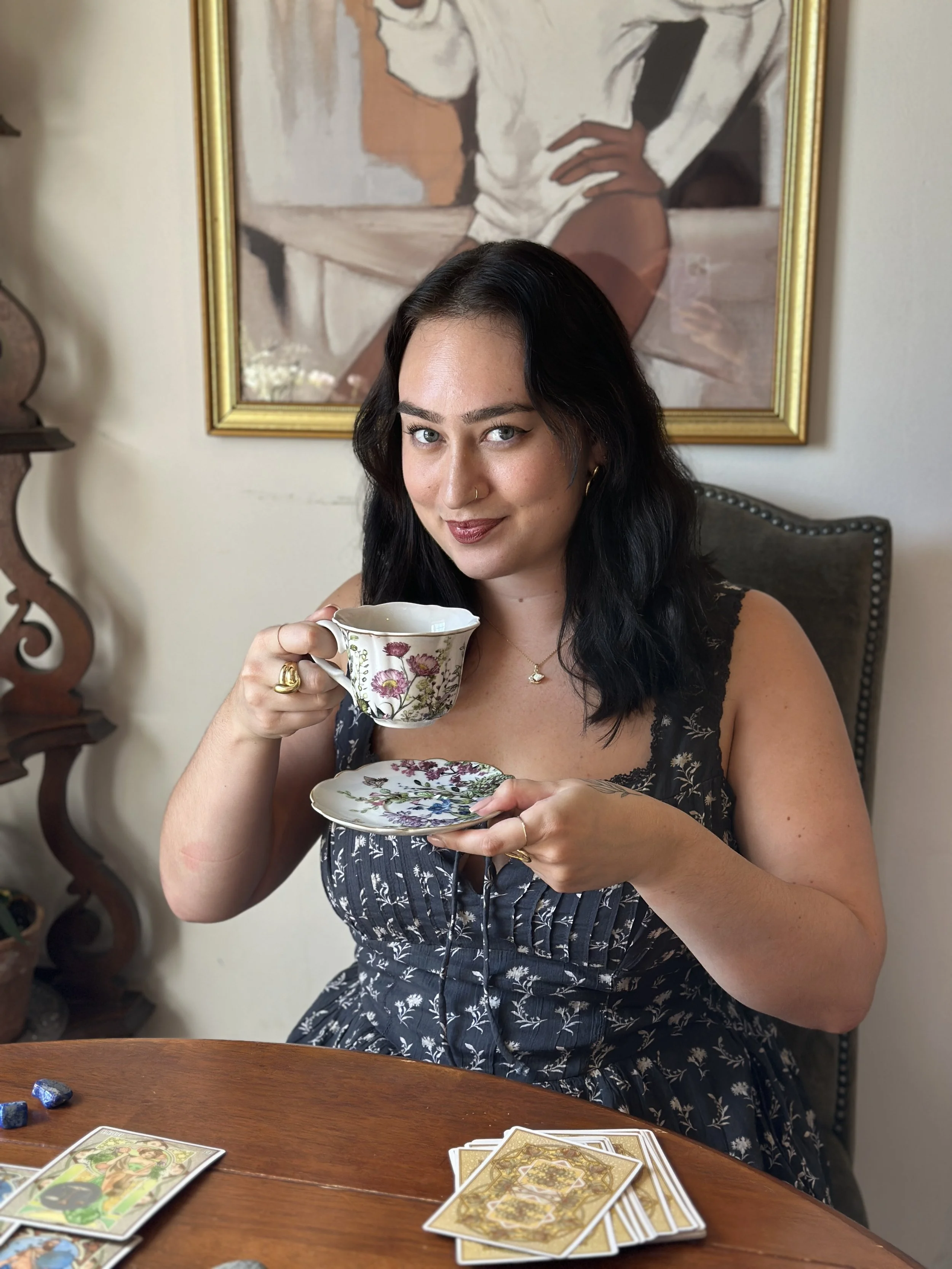 Black haired woman smirking holding a teacup and saucer