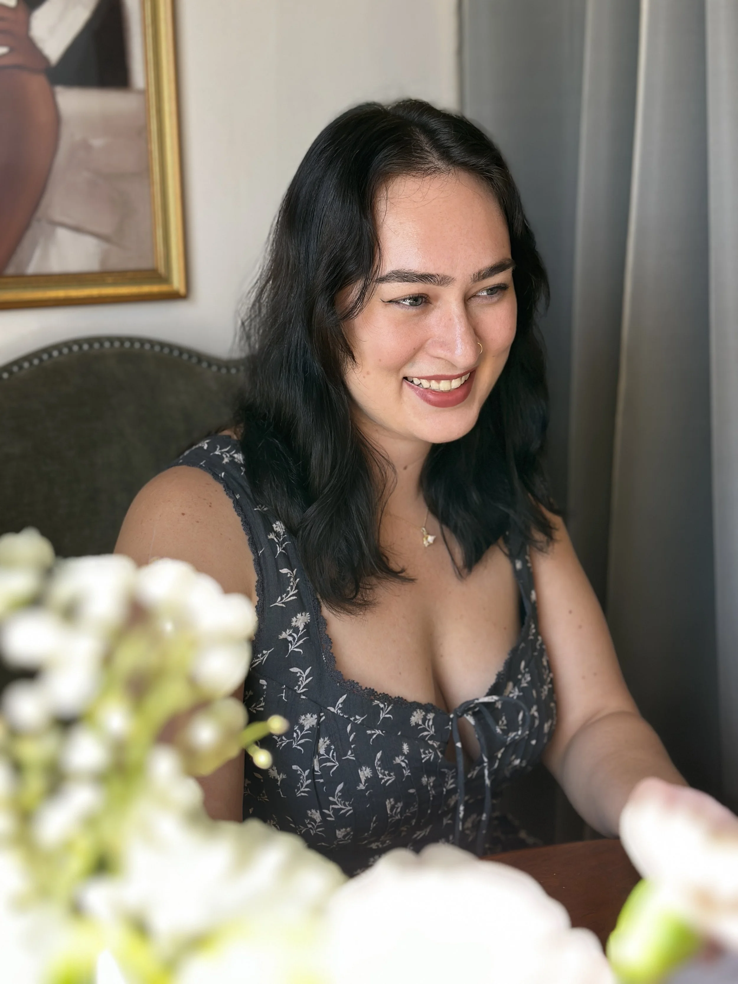 Black haired woman in grey navy top smiles
