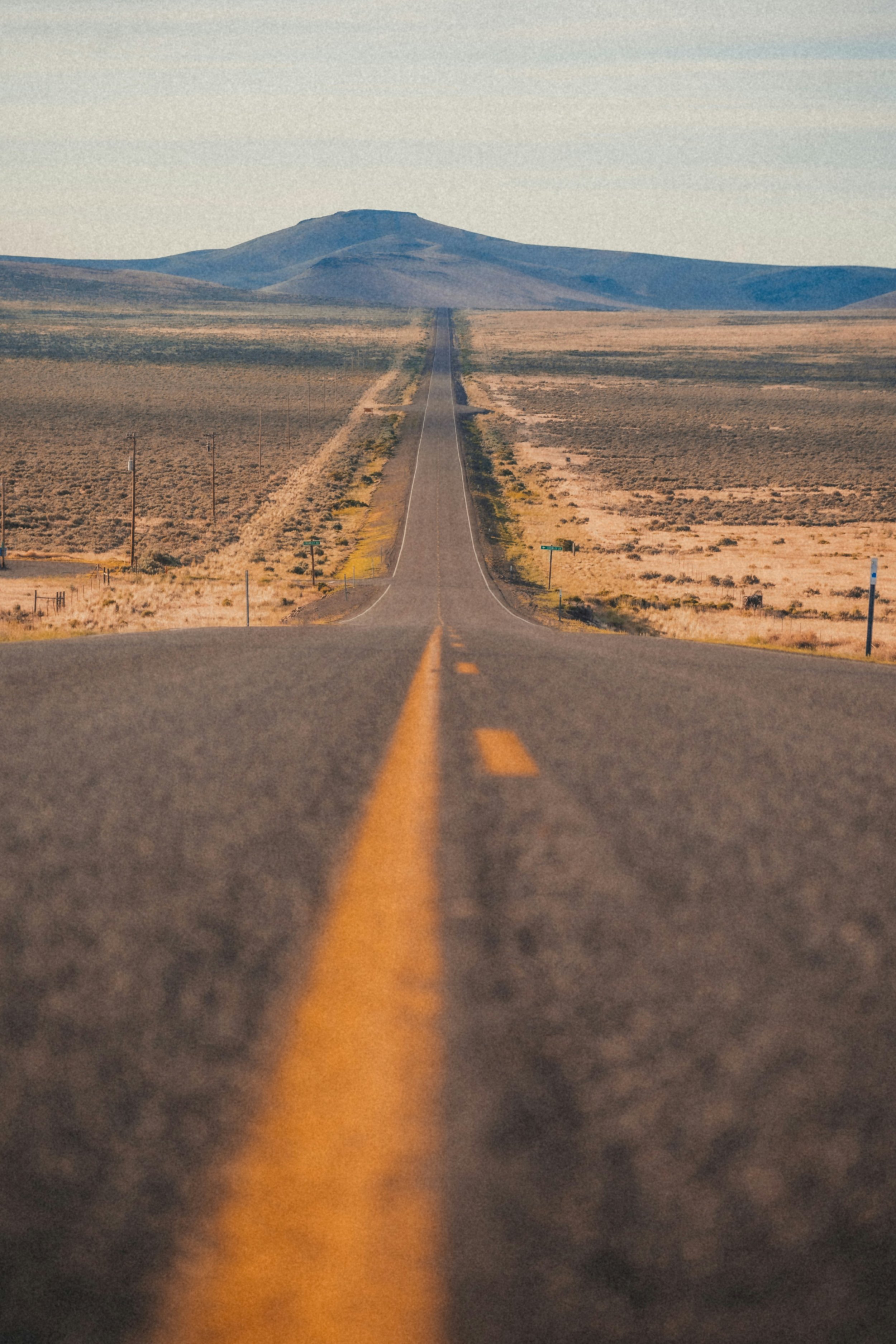Close up of a road going down hill and into the mountains in the distance