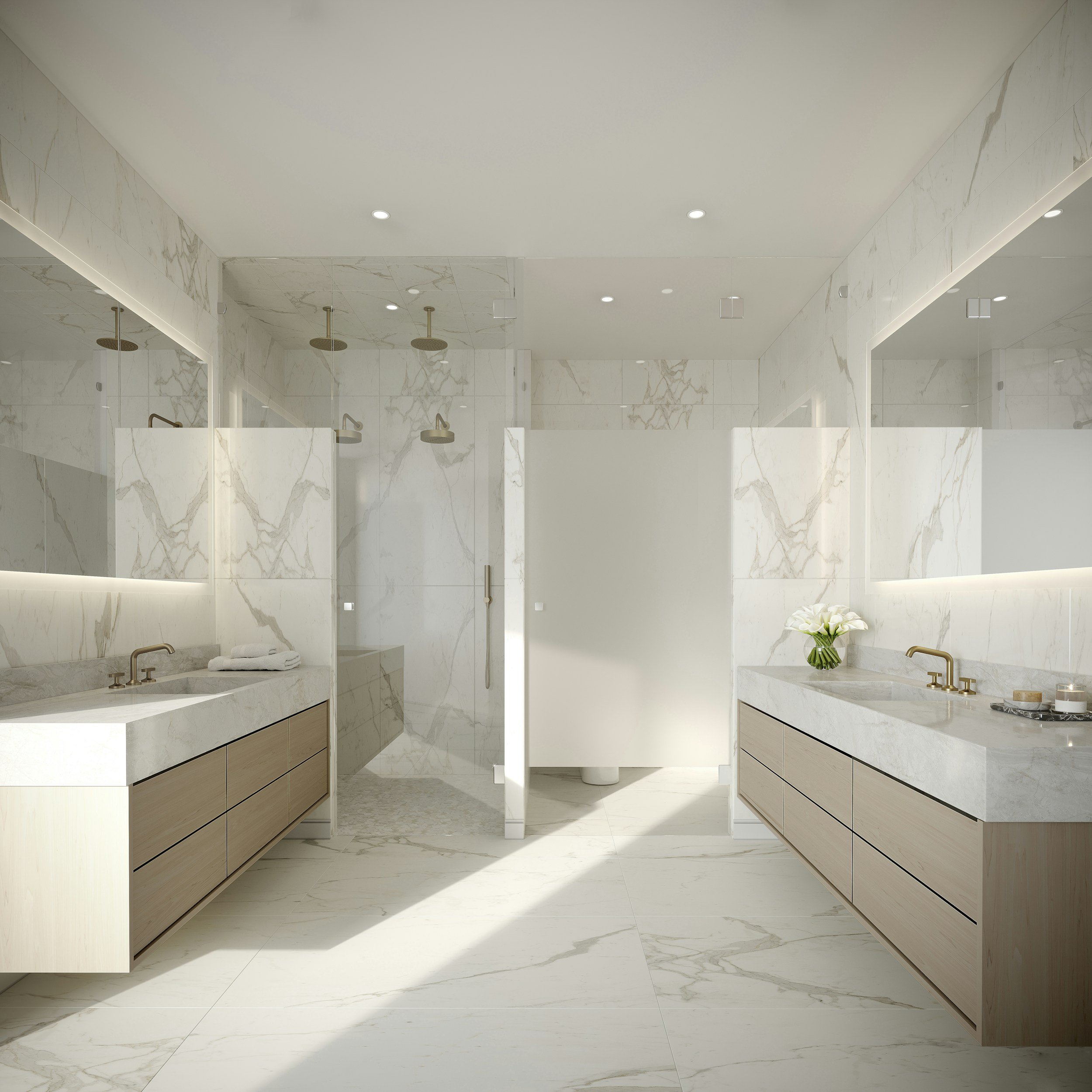 Modern restroom with white marble walls and floors, two sinks with brass fixtures, and a floral arrangement on the right counter.