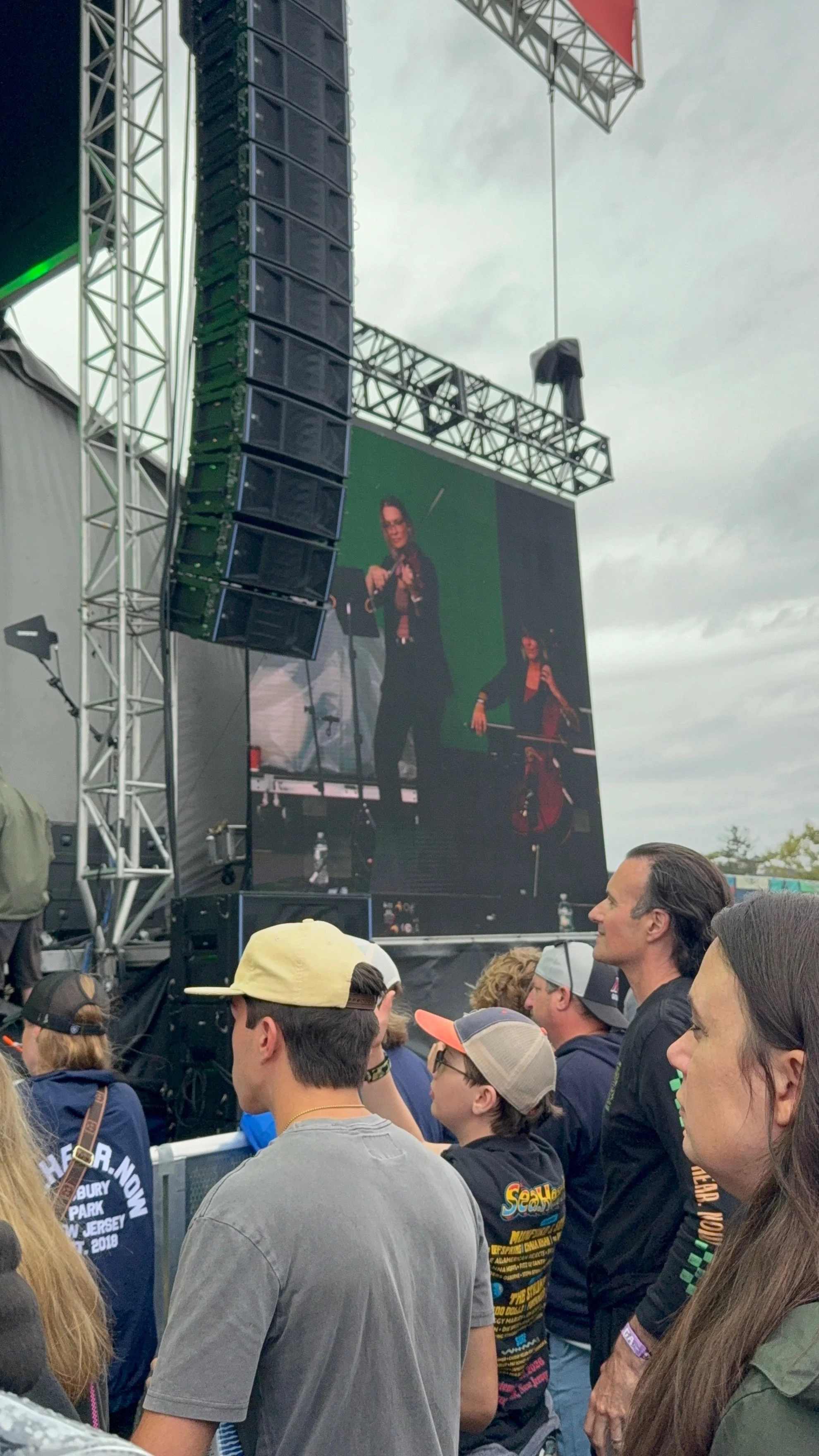 On stage big screen: Haley Schilla Plays violin at Sea. Hear. Now. Festival in Asbury Park, New Jersey. September 2026. With Status Green band.