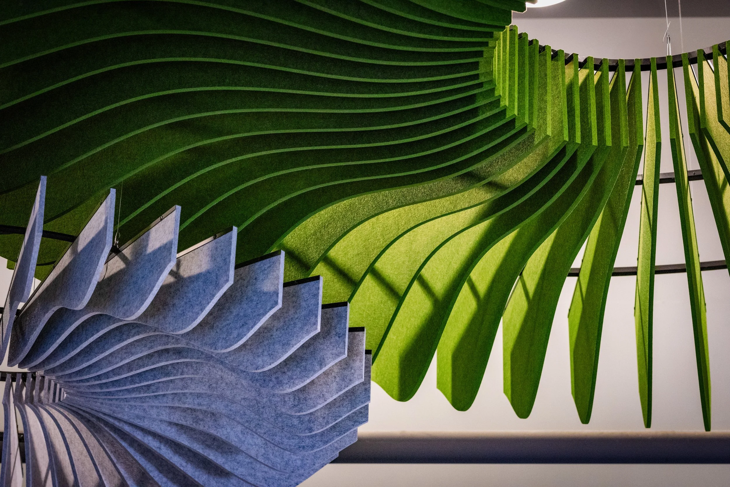 A modern staircase with green and gray curved steps viewed from below.
