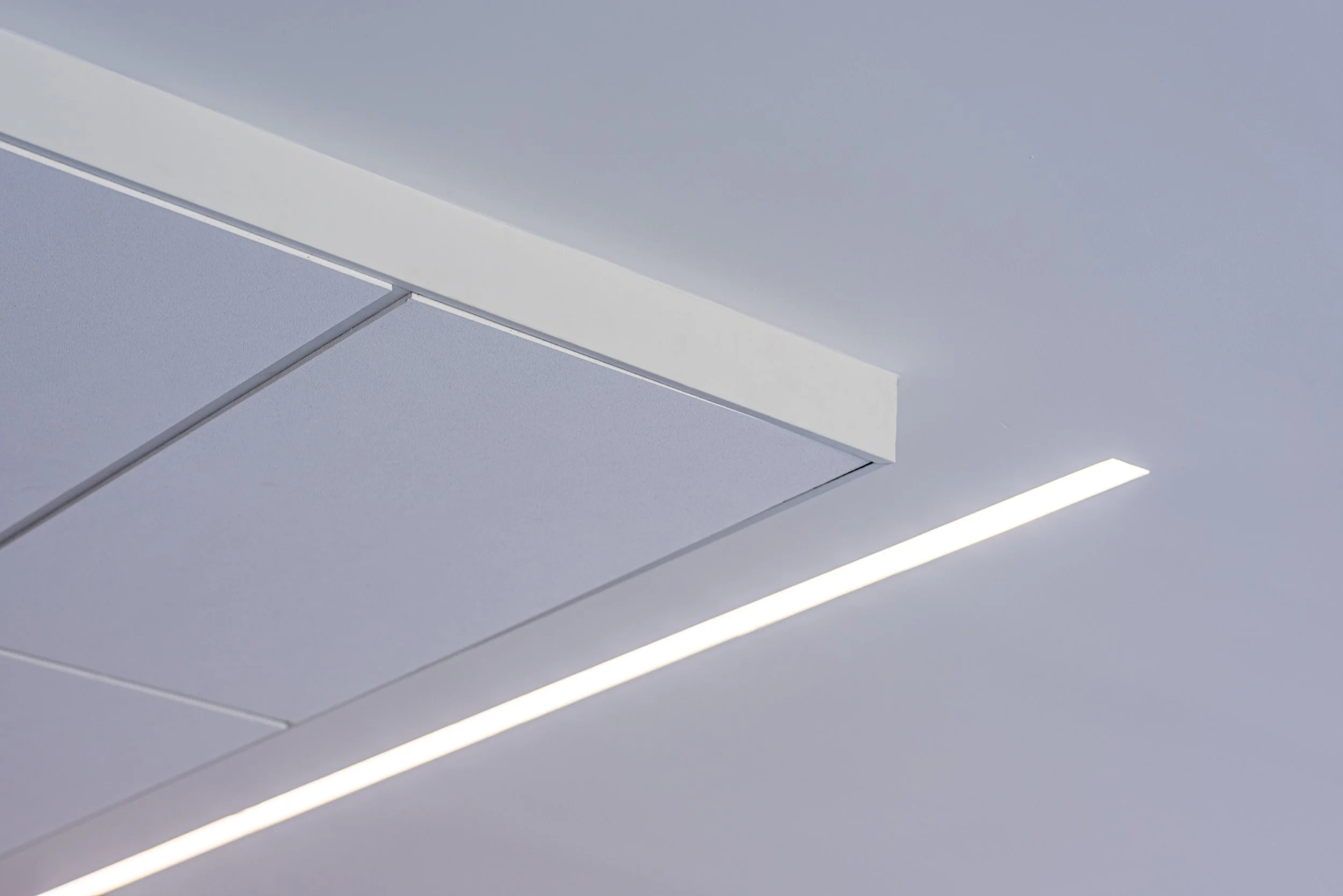 Ceiling with white rectangular air conditioning vent and linear recessed lighting.