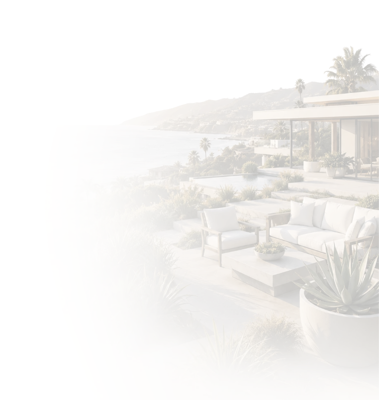 Outdoor patio with white furniture, potted plants, and a view of the ocean and hillside with palm trees.