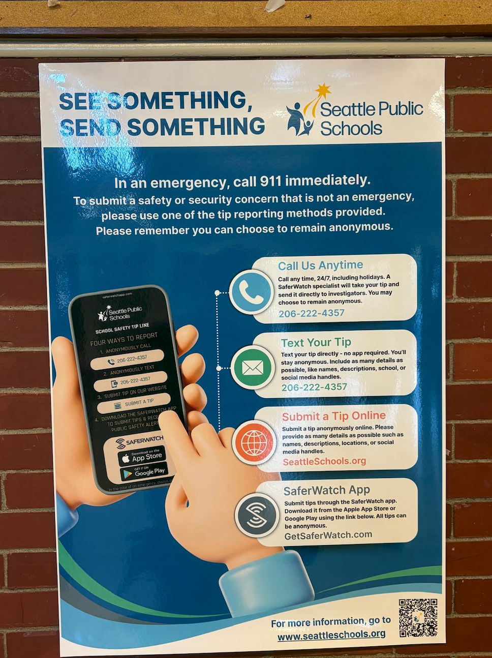 A photo of a SaferWatch poster in an SPS hallway. The poster headline reads, "See something, send something."