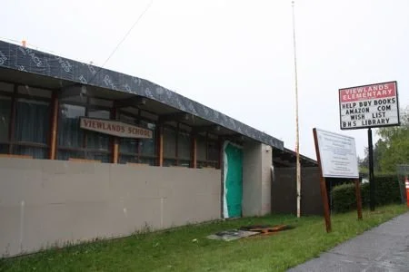 A photo of the old Viewlands Elementary during its closed years. It is peeling and run down, and debris sits in the yard.
