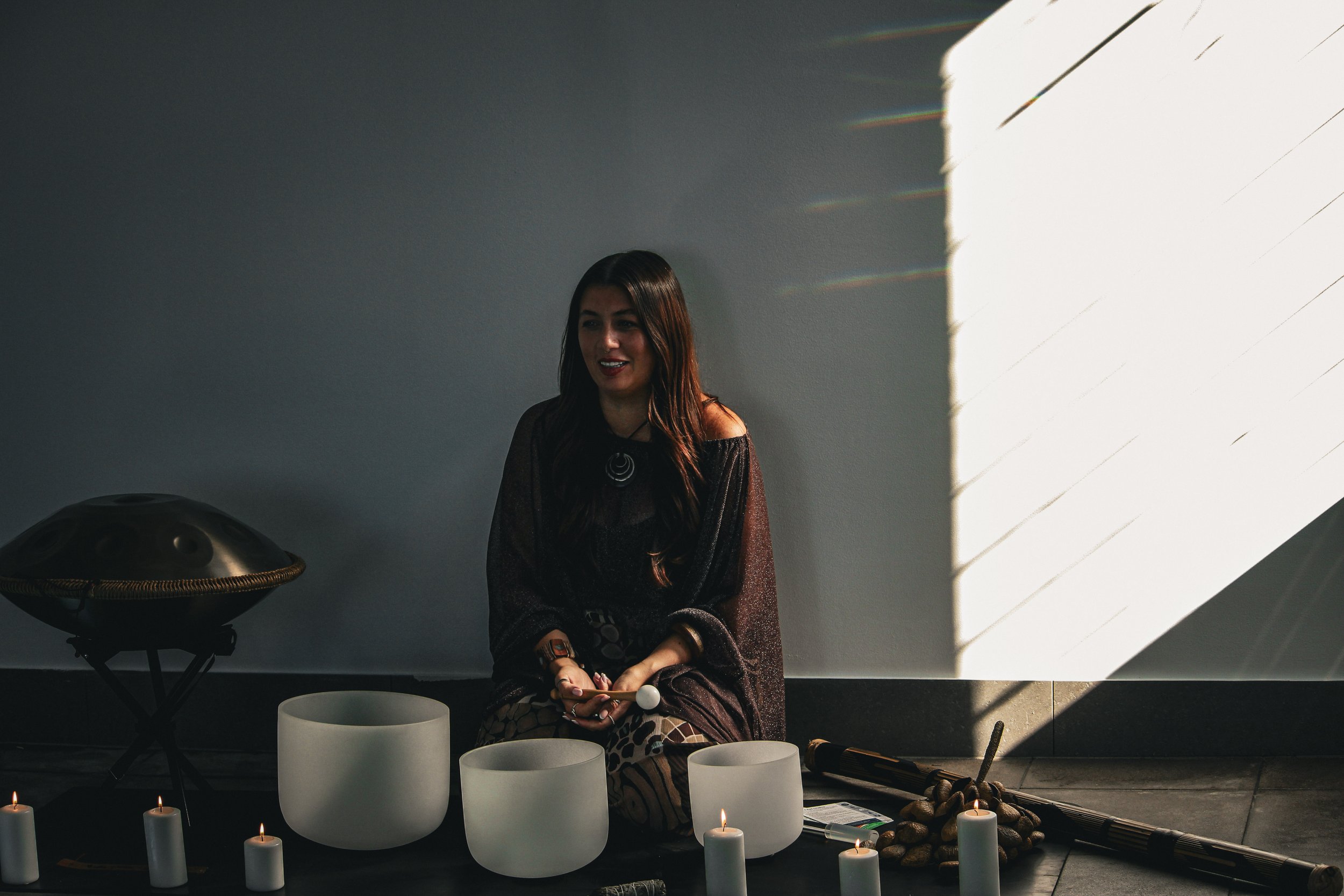 brown haired woman by the pool playing sound baths at a wellness retreat while smiling