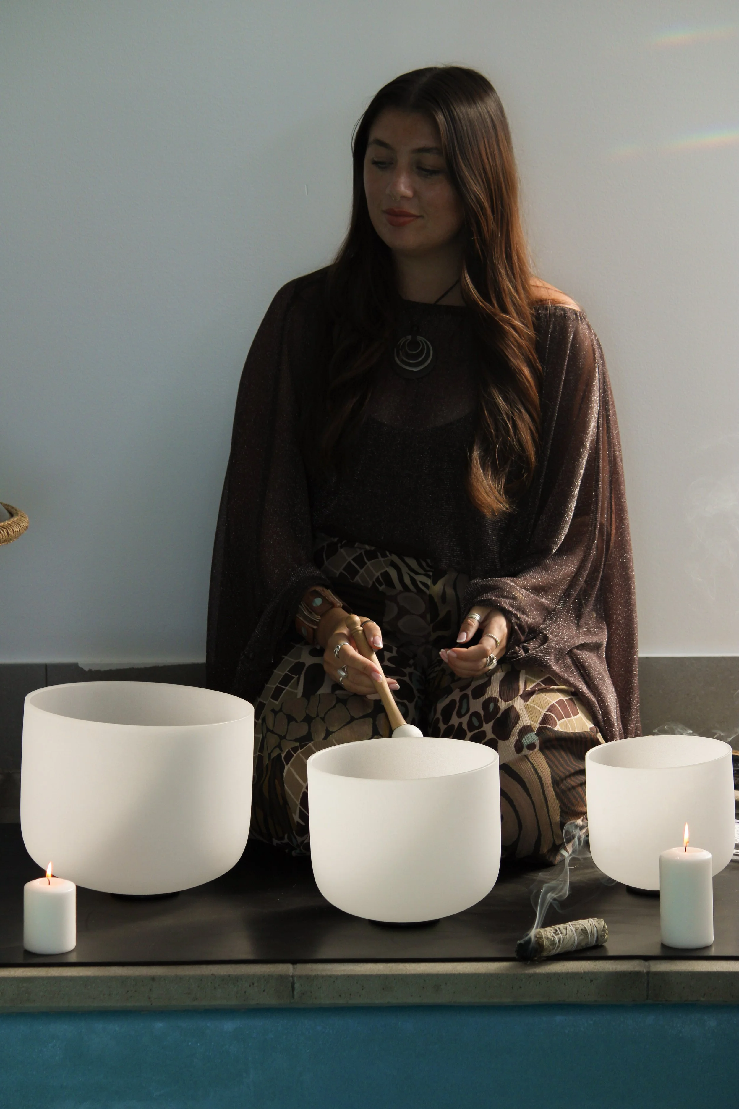 brown haired woman by the pool playing sound baths at a wellness retreat