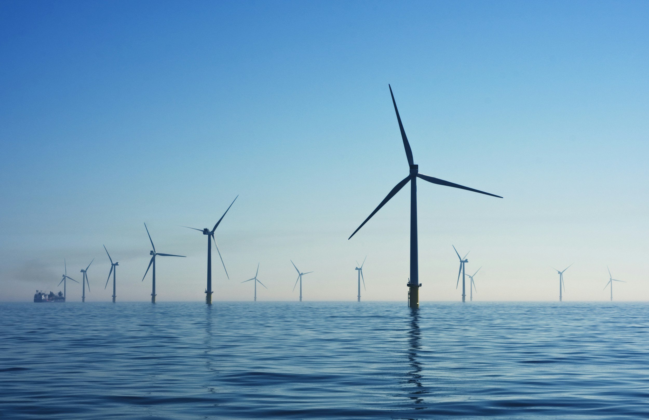 Offshore wind turbines in the ocean with a ship in the background