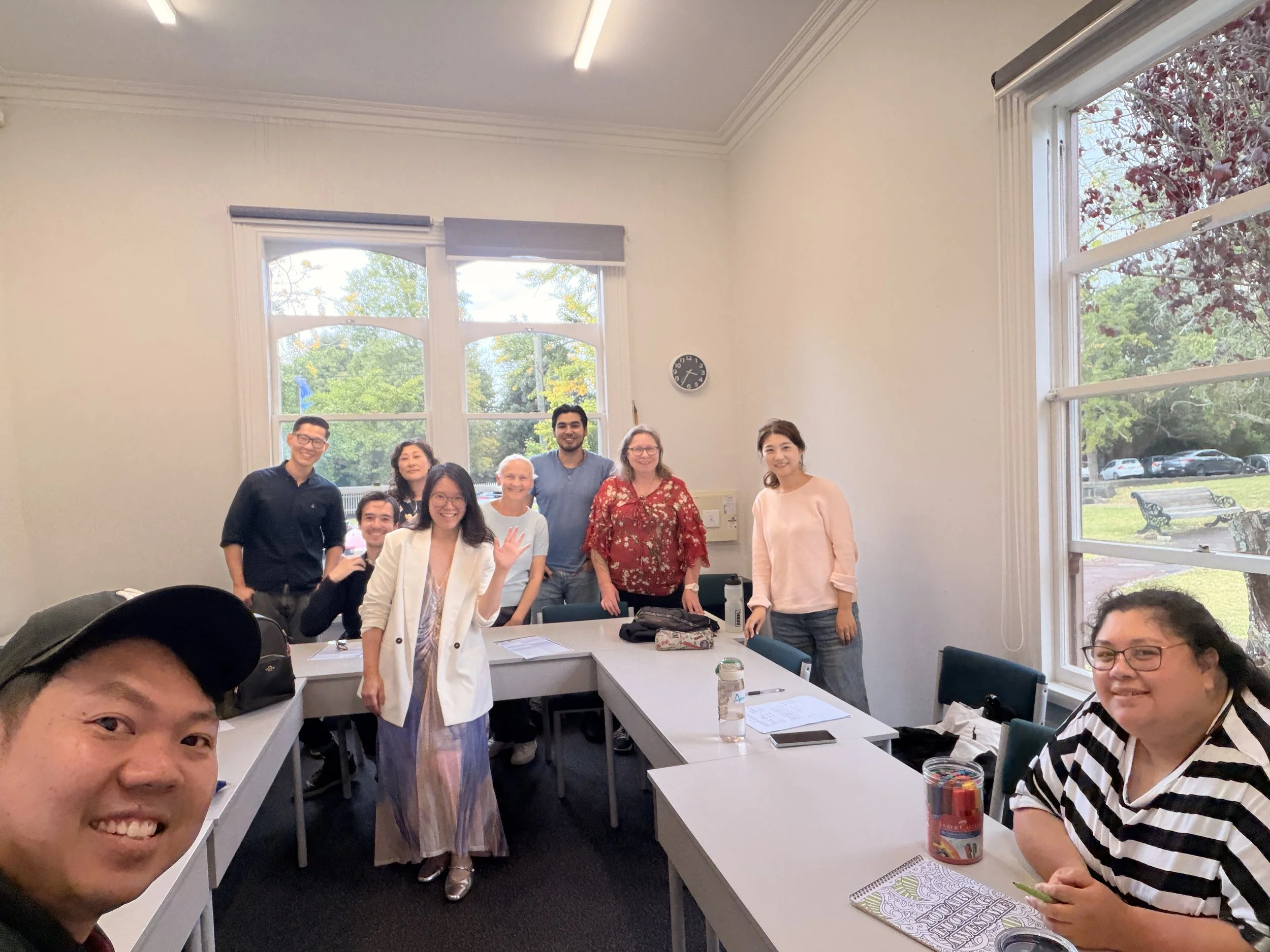 Adult English students and teacher taking a group selfie after completing a short English course