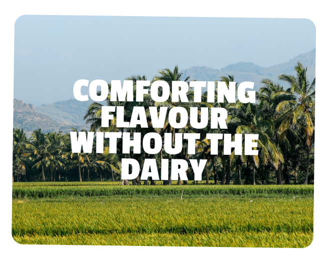 A scenic landscape of green fields with palm trees and mountains in the background, overlaid with the text 'Comforting flavor without the dairy'.