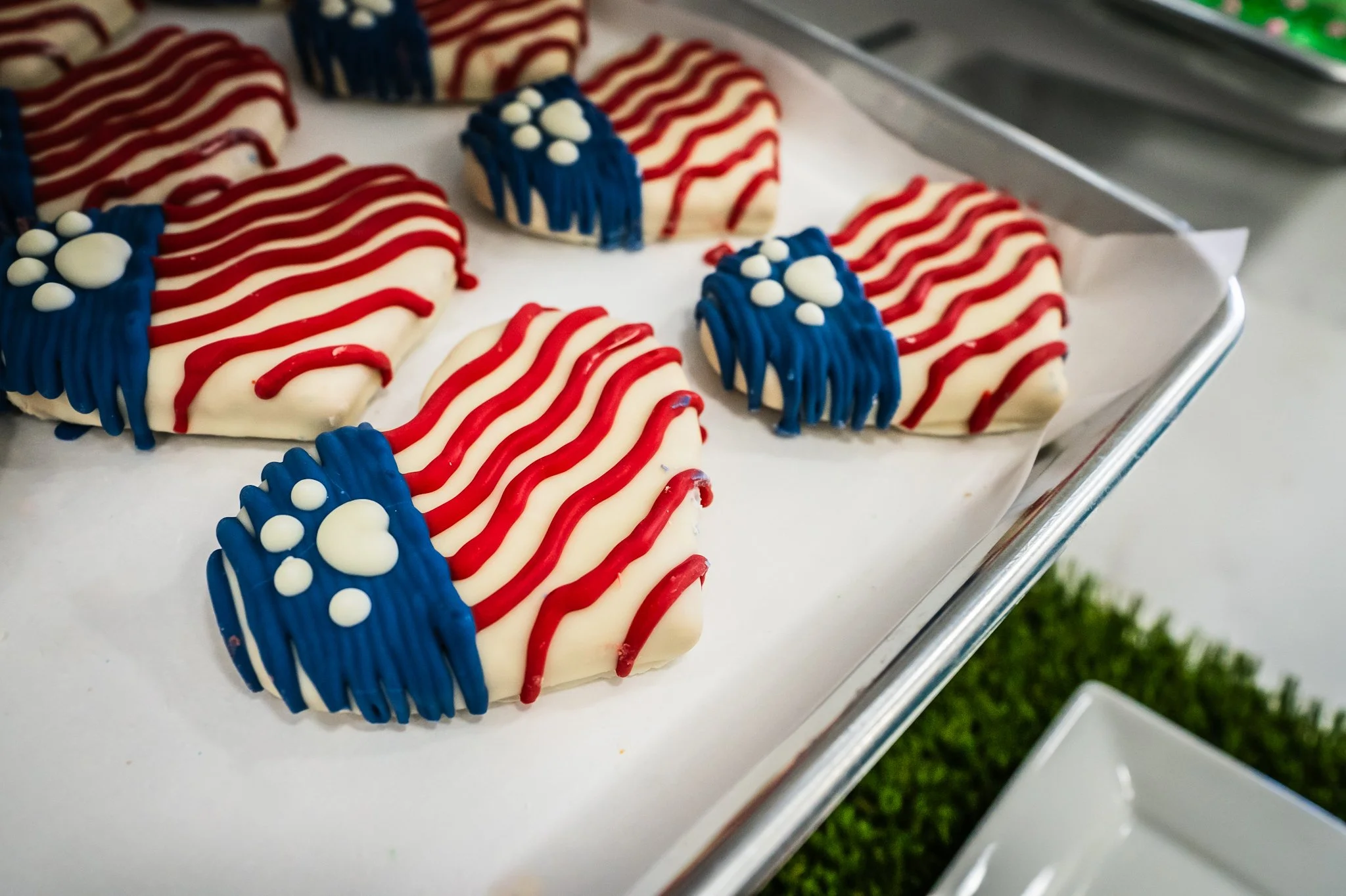 Patriotic cookies decorated with red, white, and blue icing in the shape of stars and stripes, on a tray.