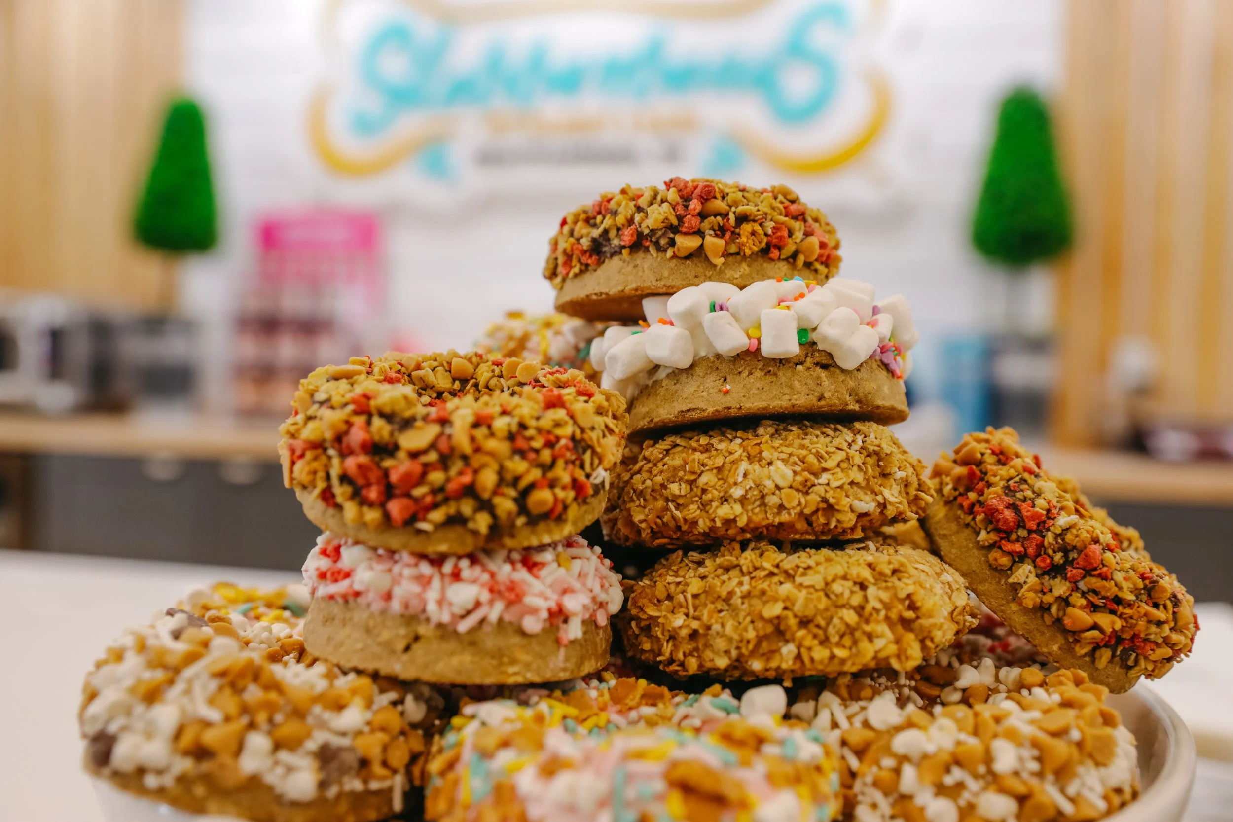 Assorted cookies decorated with sprinkles, crushed candies, and toppings, stacked on a white plate.