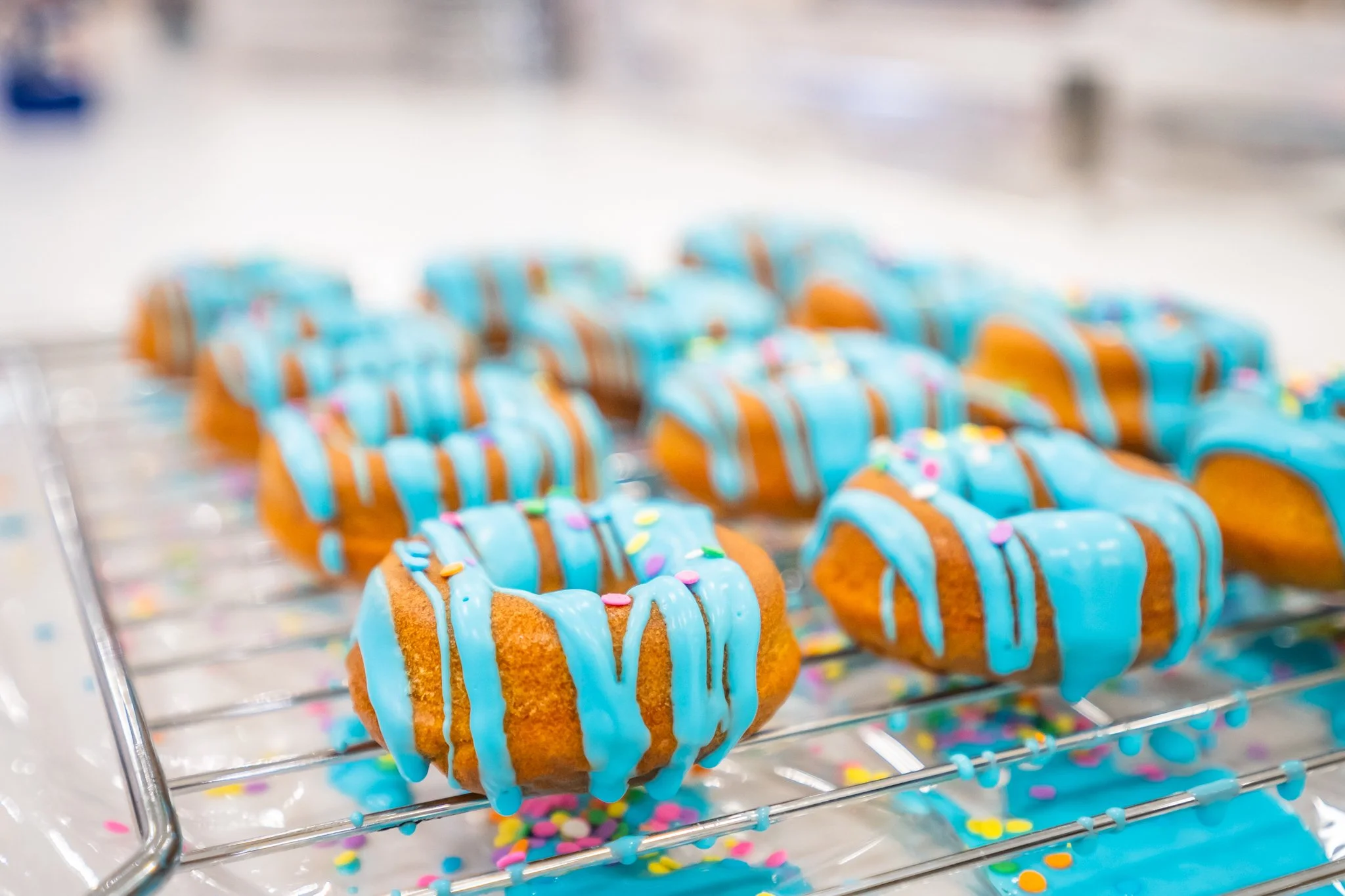 Close-up of decorated cookies with blue icing and colorful sprinkles on a wire rack.