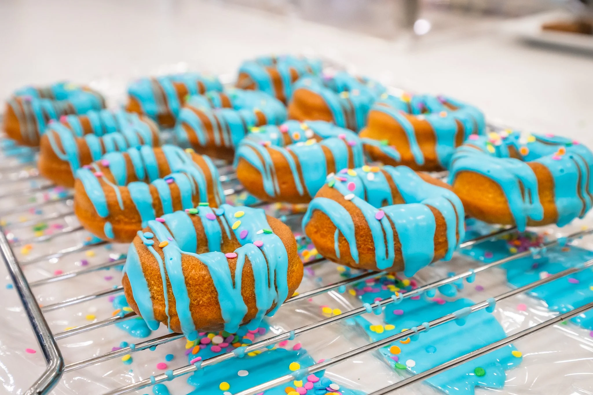 Close-up of a tray of decorated donuts with blue icing and colorful sprinkles.