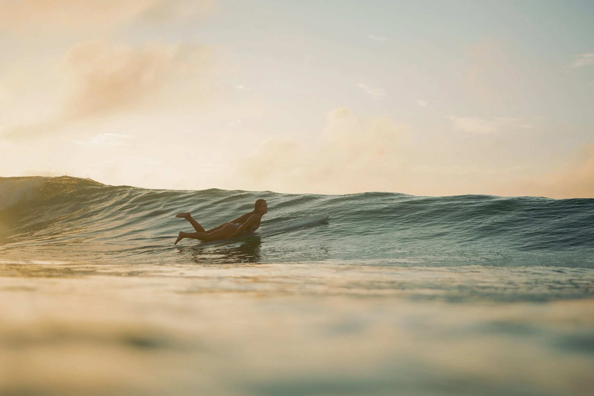 Woman paddling out over a wave on a surfboard