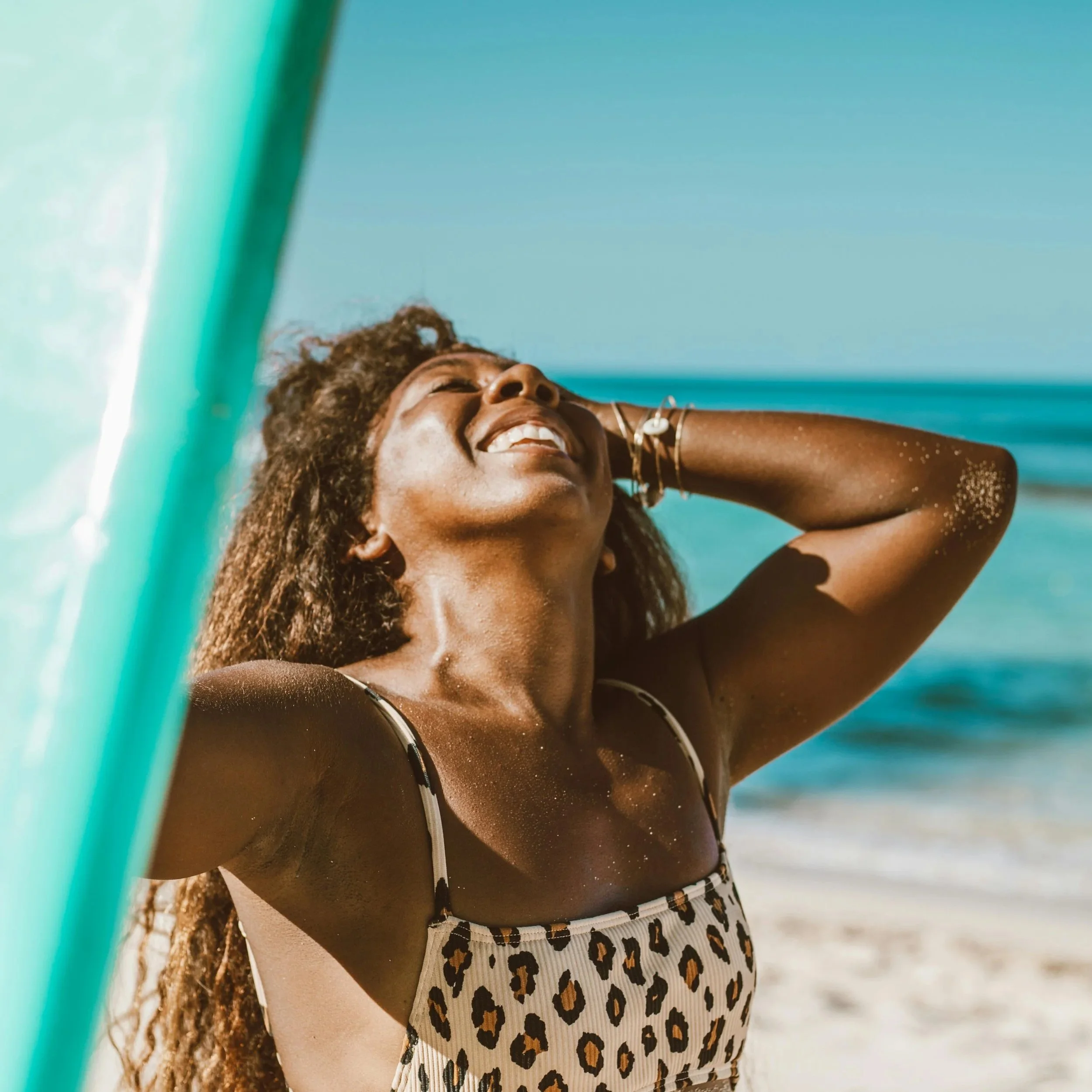 Woman smiling in the sun while standing on the beach.