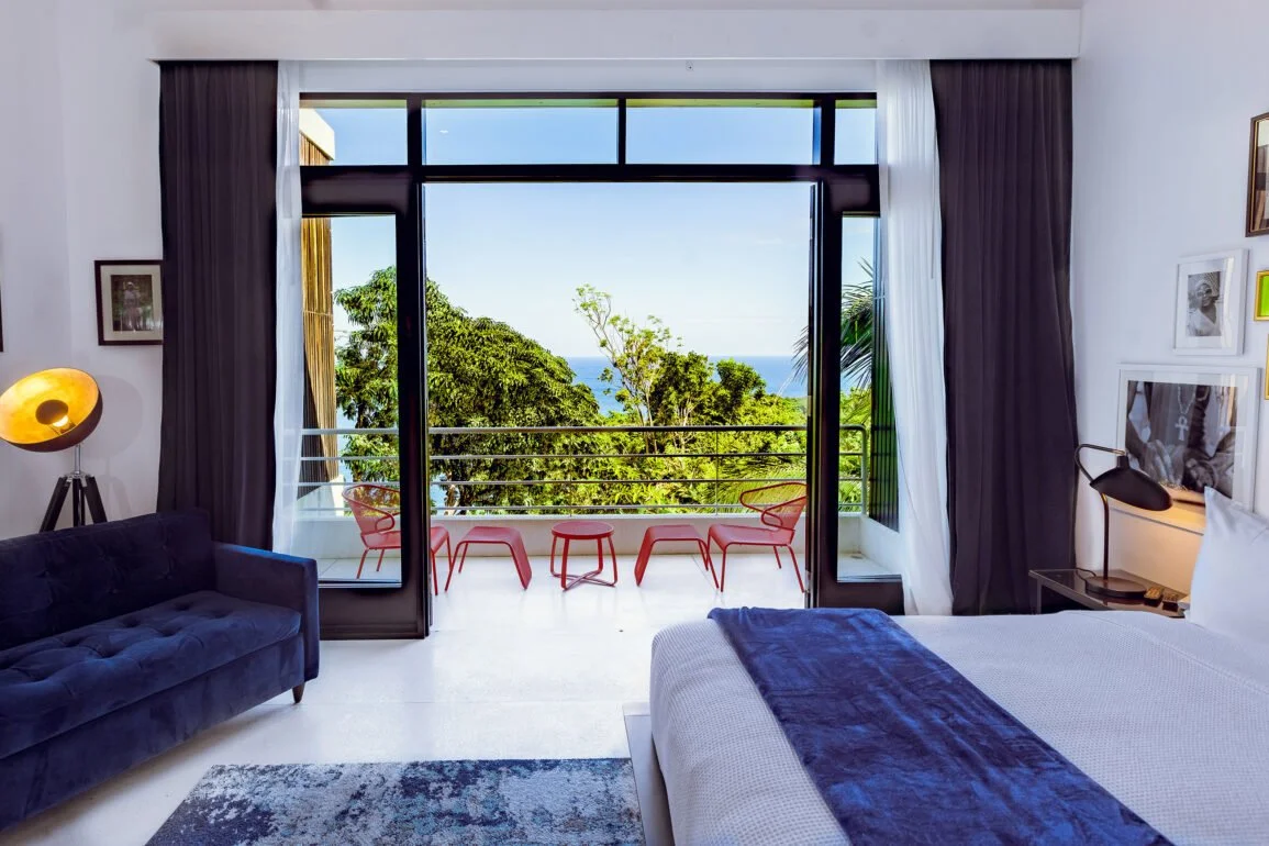 Private Rumba Room– a hotel room with balcony view overlooking tropical greenery.