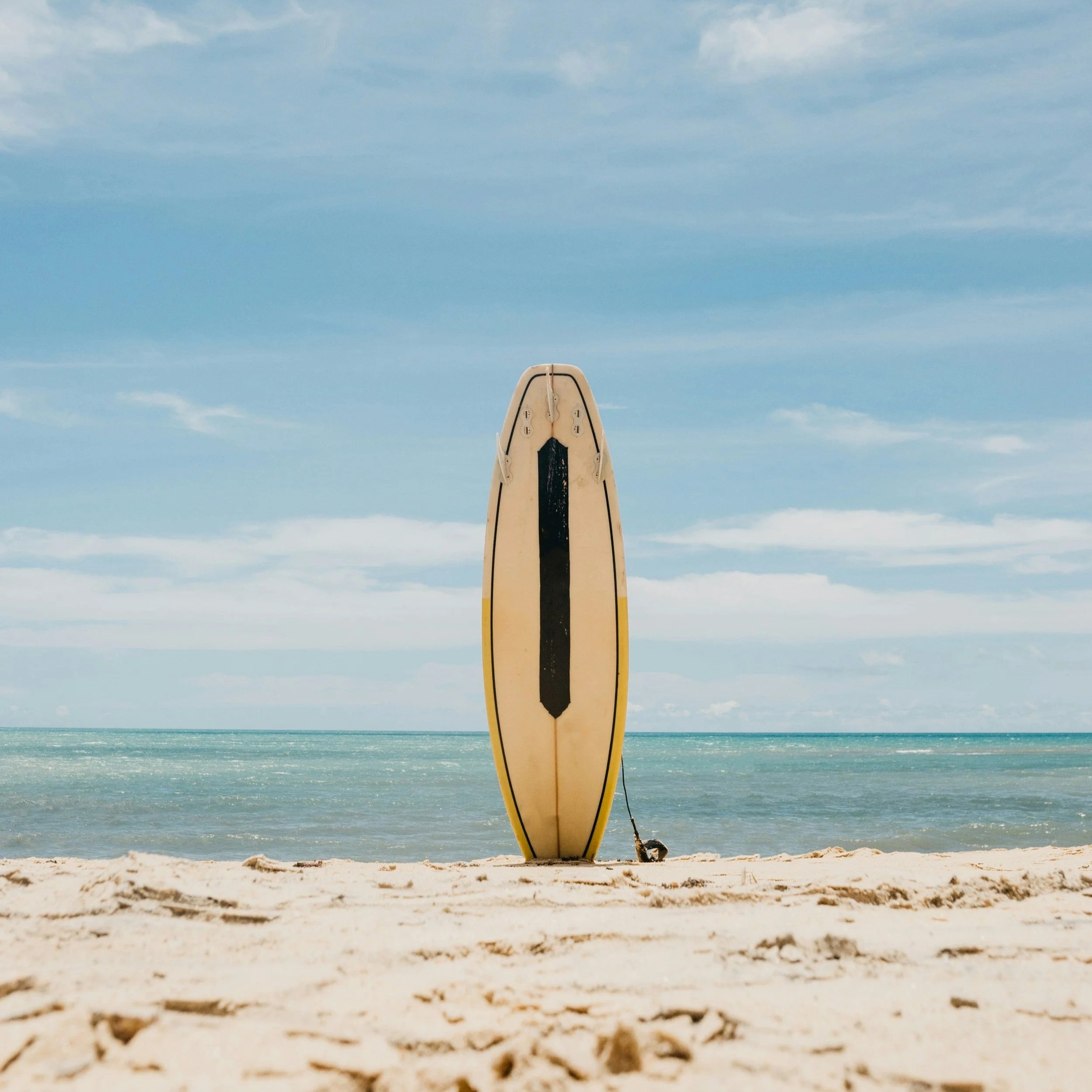 Yellow surfboard on a beach with turquoise ocean water