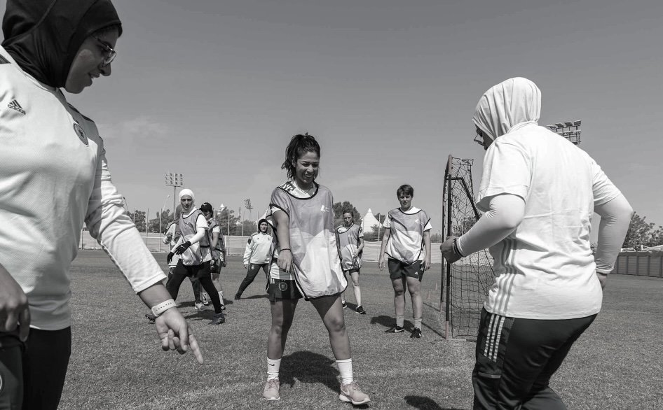 Women on a soccer field with young players, some wearing training vests, in a training or coaching session.
Doha, Qatar. Sport for development. Women's sport. Women's football