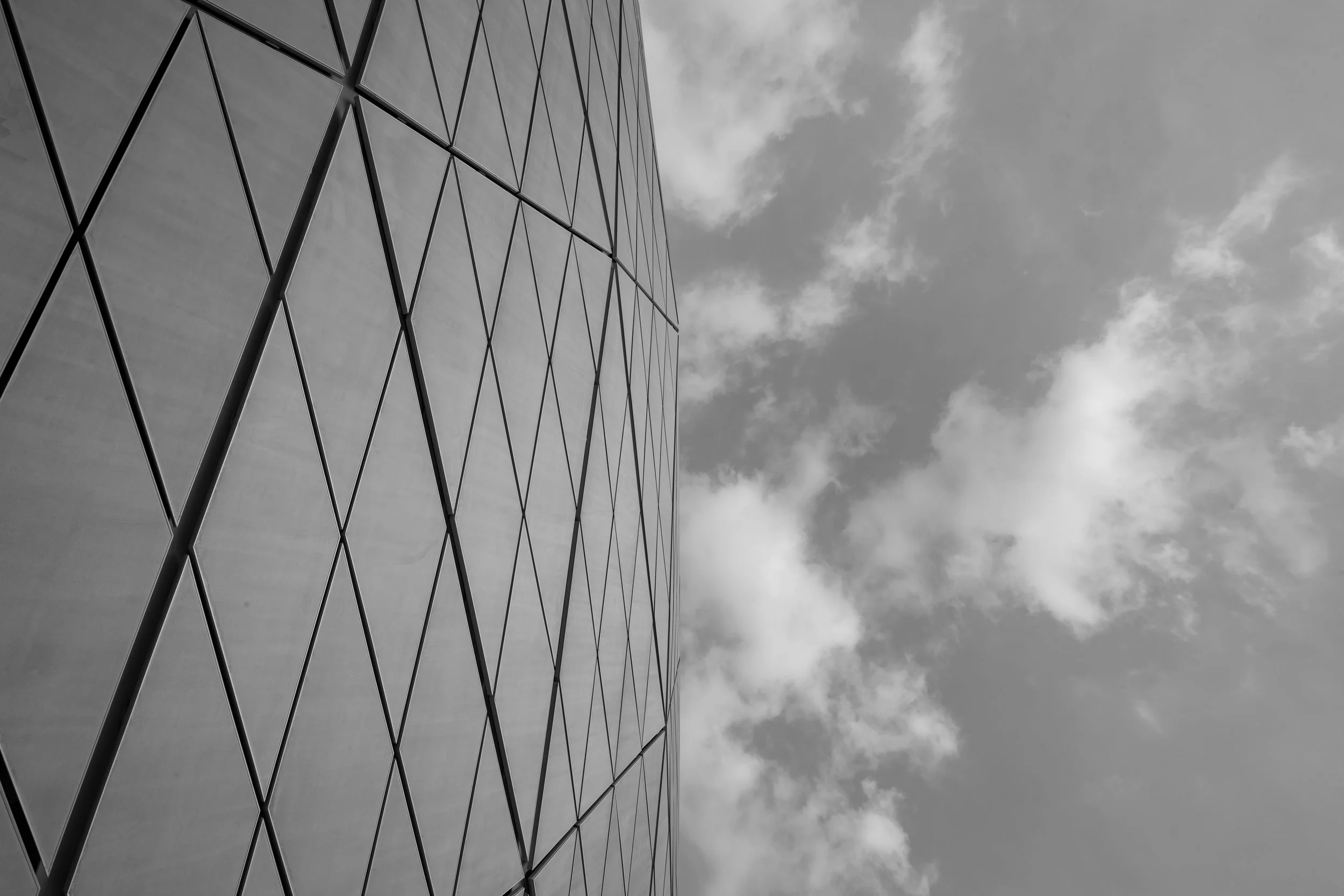 A modern building with a geometric glass facade reflects a cloudy sky.
Education City Stadium. Doha, Qatar