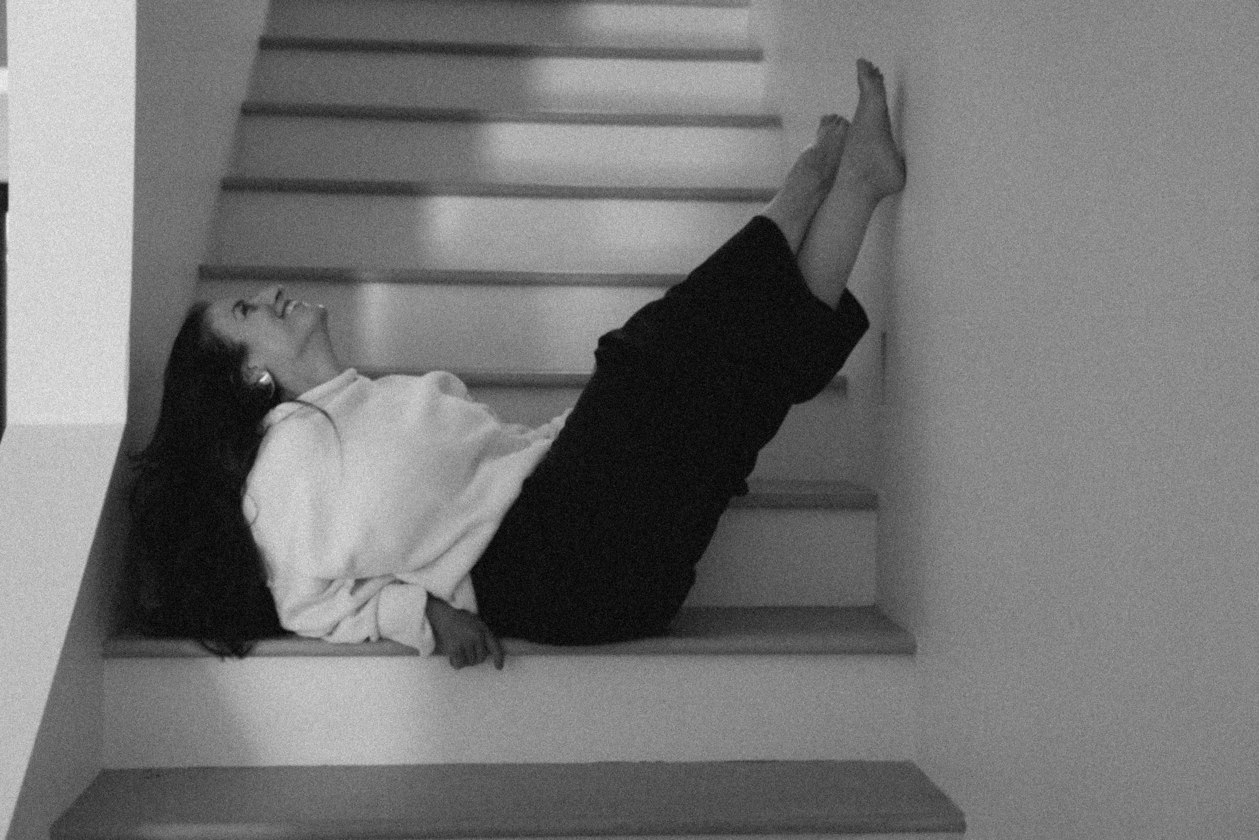 Woman resting on staircase in a moment of softness and restoration.