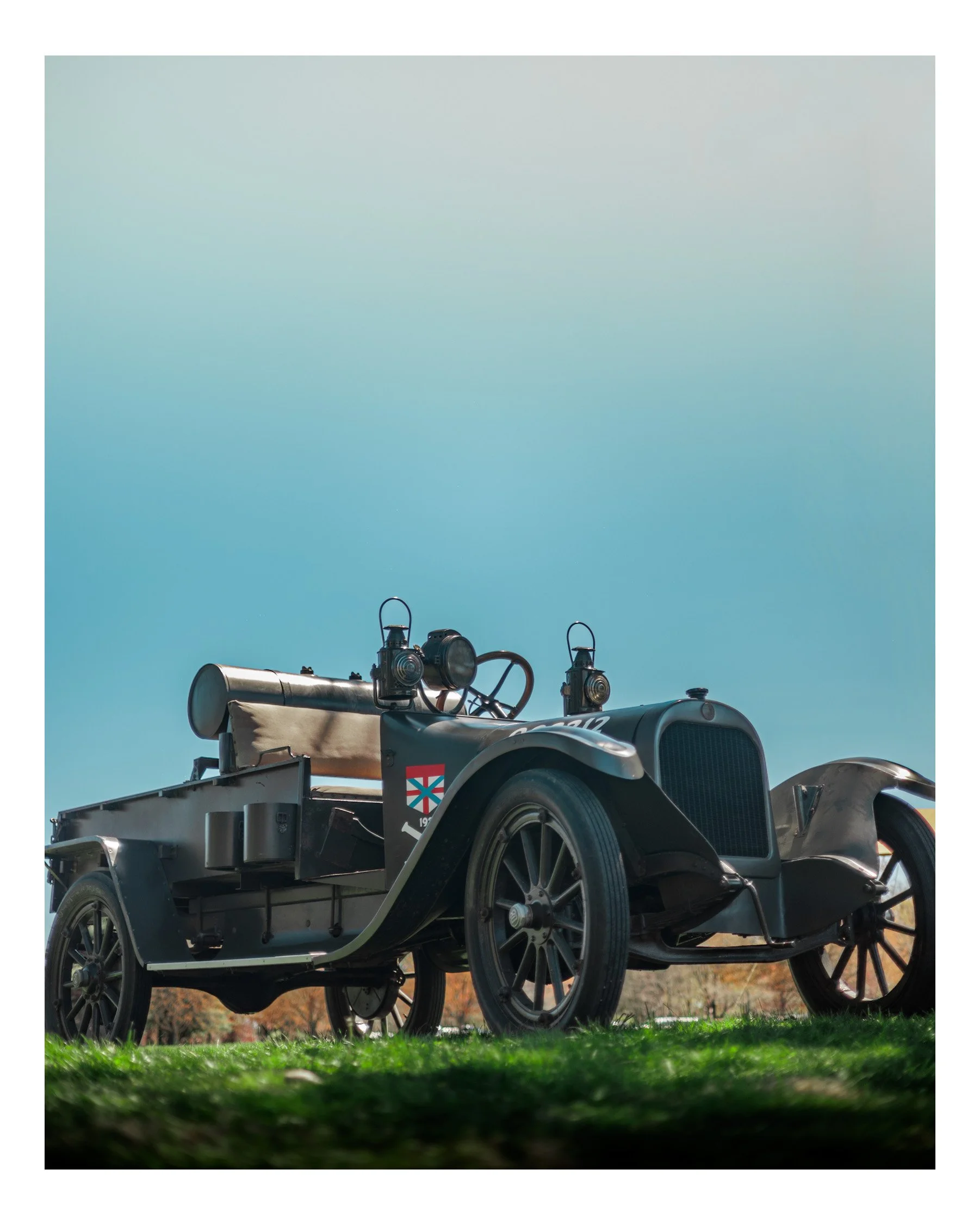 Close-up of a vintage military jeep parked outdoors on grass with a clear sky background.