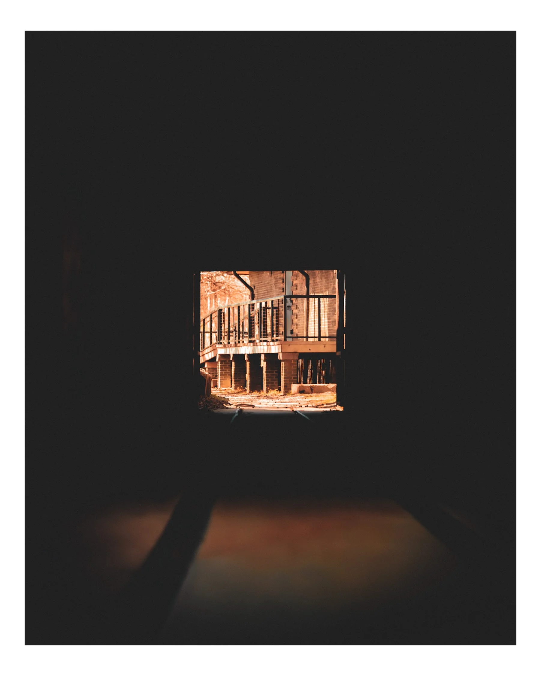 View of a fire escape at night, illuminating a brick building with warm light, framed by darkness.