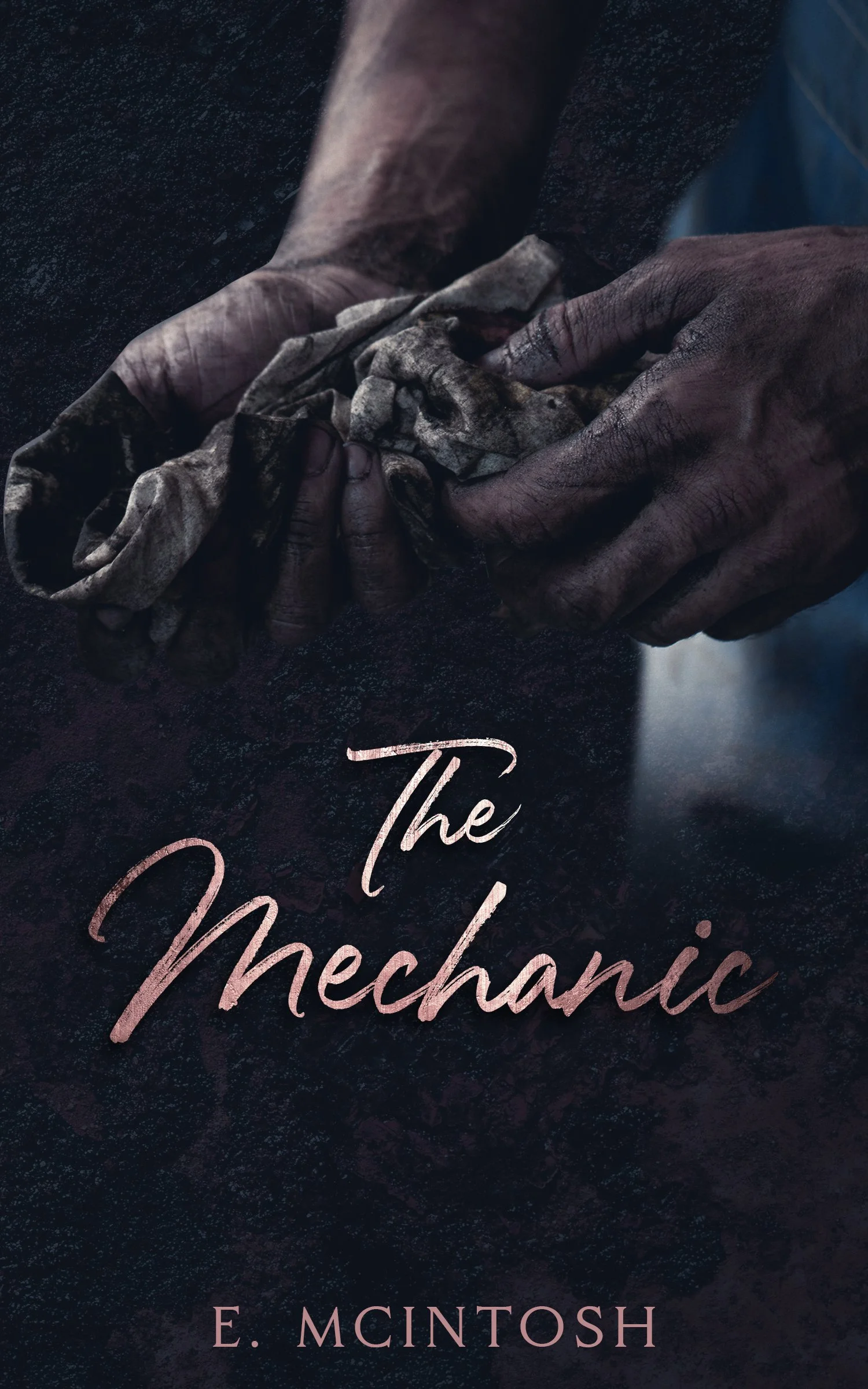 Close-up of dirty, worn hands holding a crumpled cloth over a dark textured surface, with the title 'The Mechanic' and the author's name 'E. McIntosh' displayed.