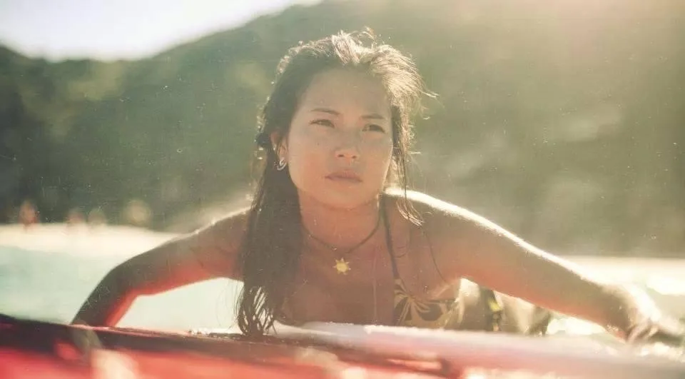 A woman swimming outdoors during daylight with sunlight shining on her face.