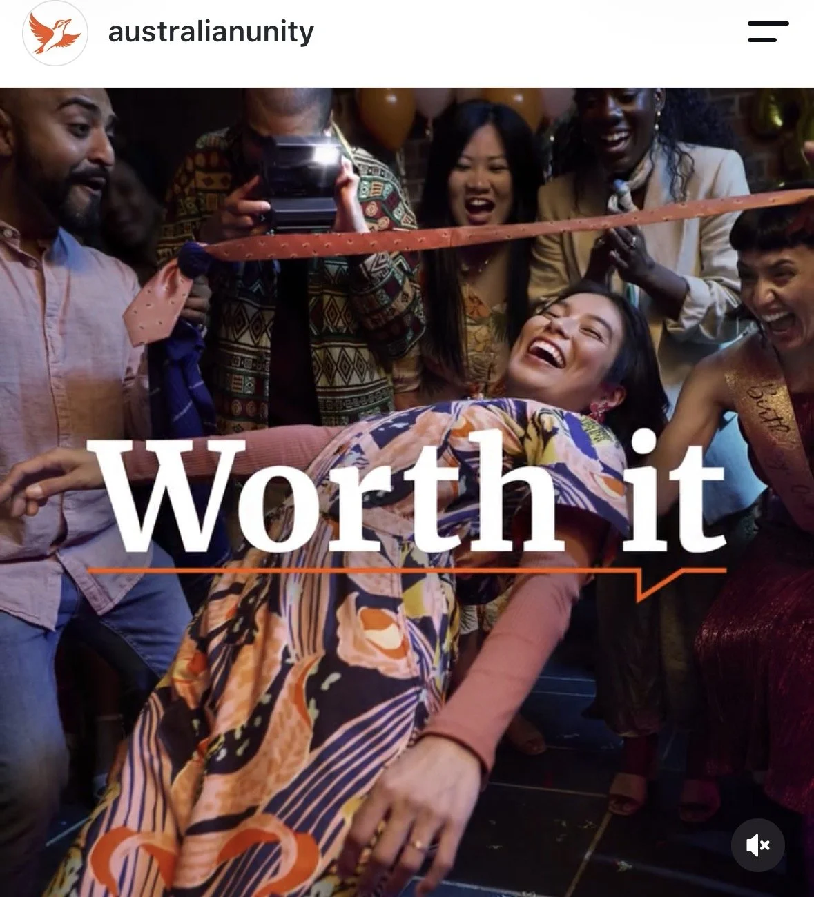 A group of people celebrating at a party, with a woman about to cross a finish line for a celebration or race. Everyone is smiling and joyful. The text says "Worth it".