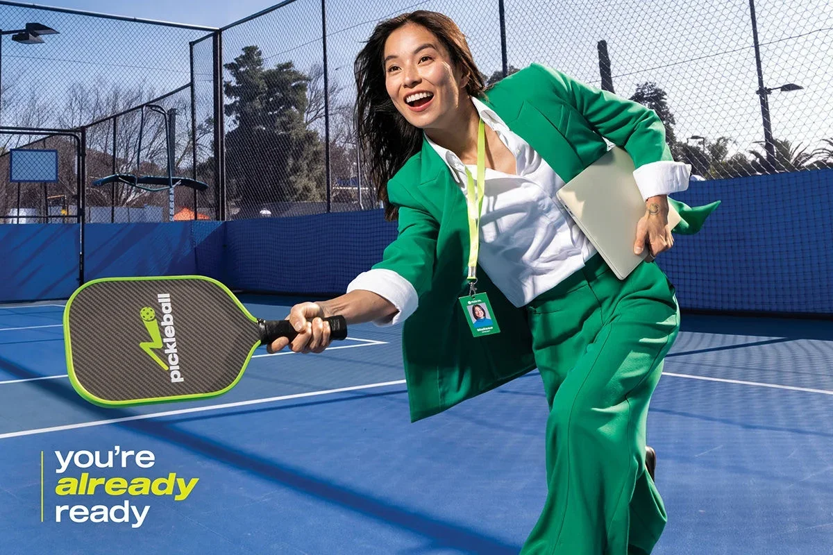 Screen showing a woman in a green blazer smiling and playing pickleball